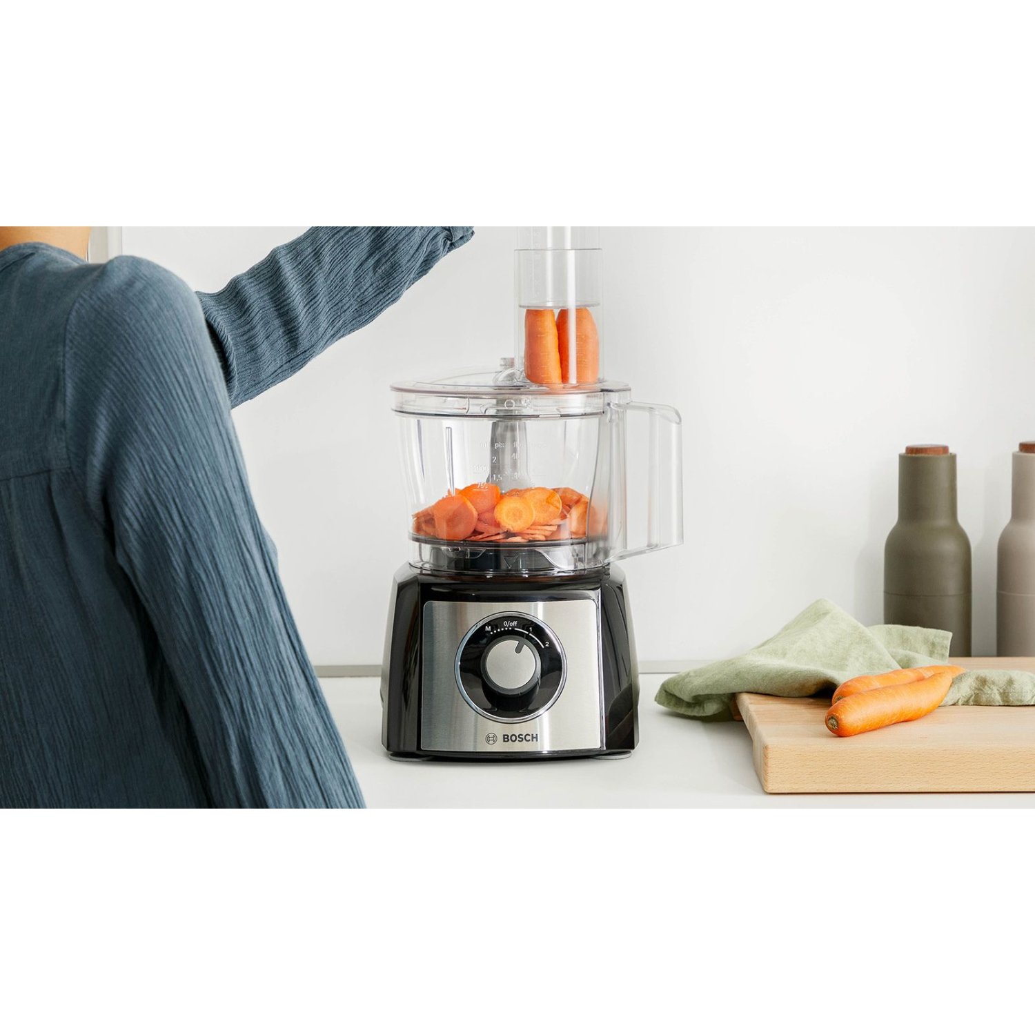 Robot kuchenny z pokrojoną marchewką i ramieniem. Tło z drewnianą deską.