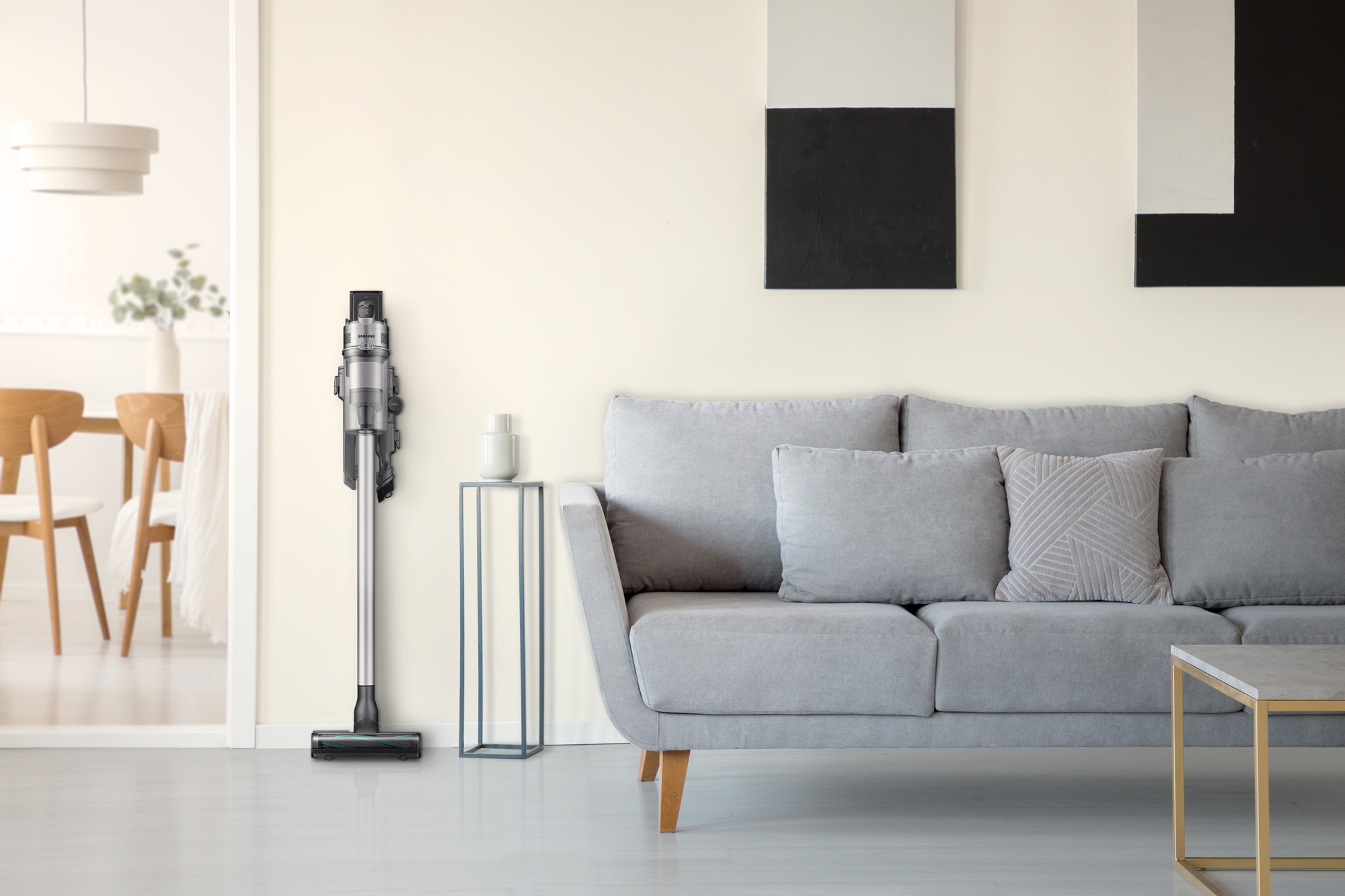 Modernes Wohnzimmer mit Staubsauger, der an einer Wand neben einem Sofa und Beistelltisch lehnt.