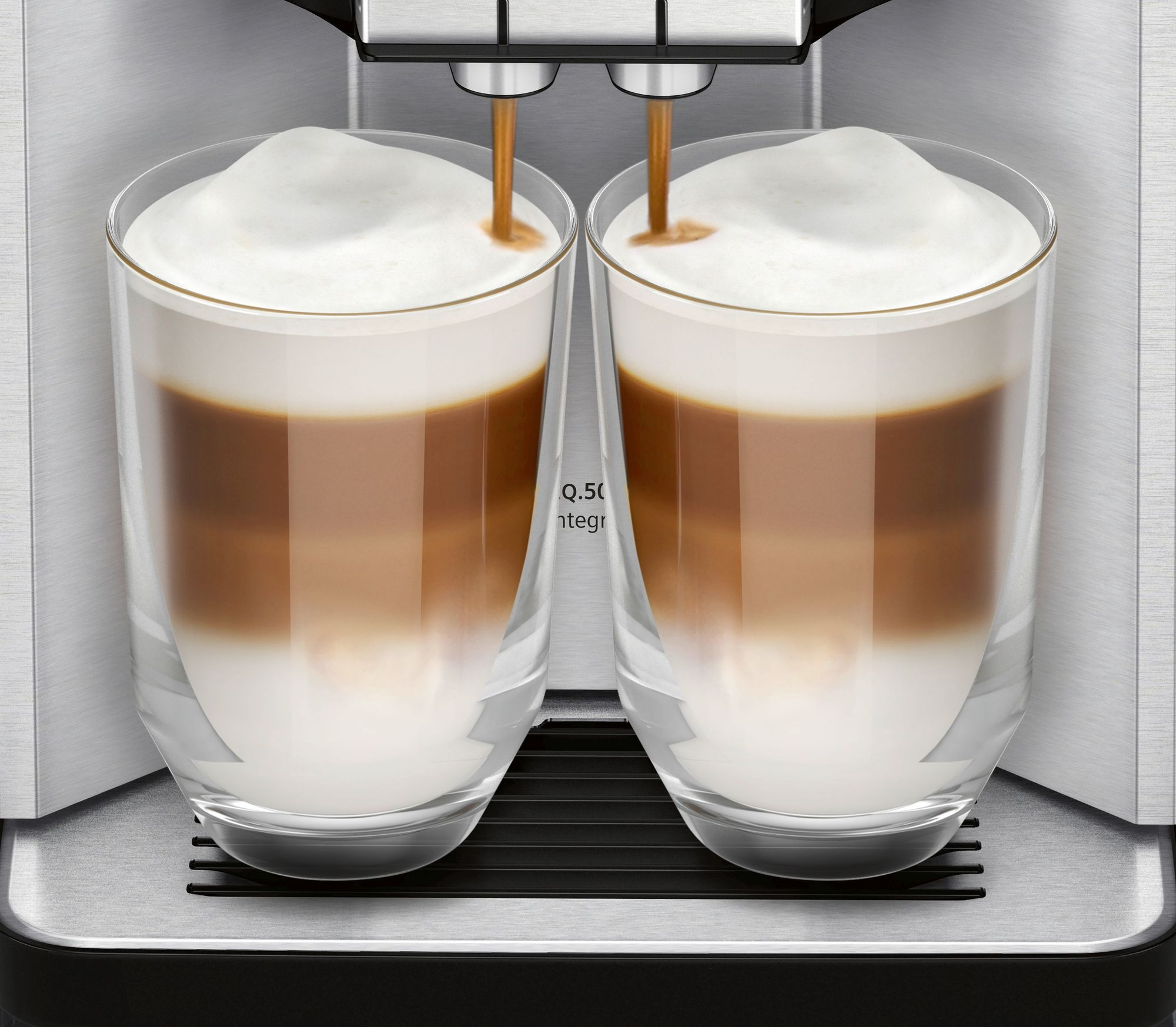Zwei klare Gläser gefüllt mit geschichteten Kaffeegetränken, die von einer Maschine ausgegeben werden.