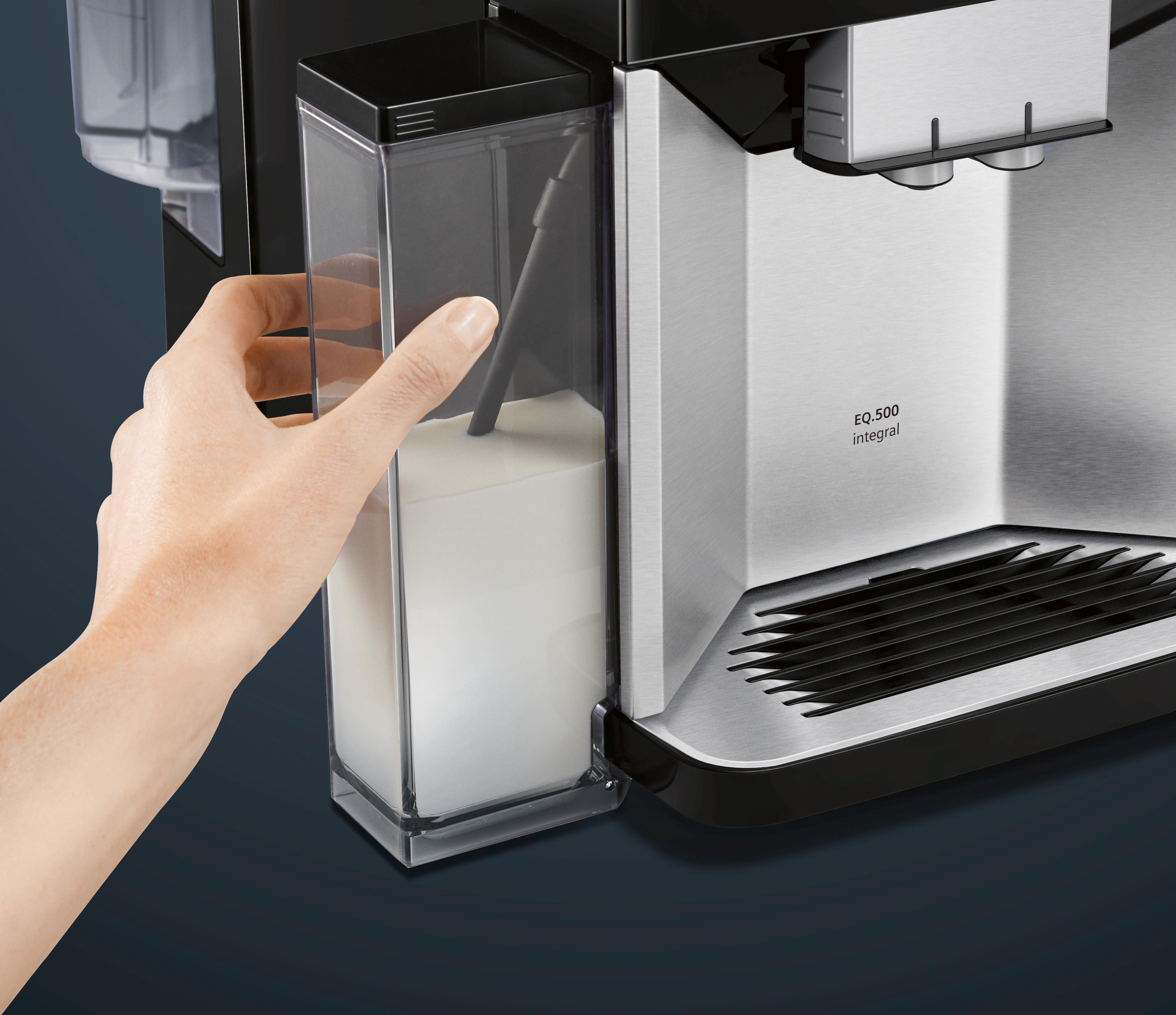 Hand füllt Milch in eine Kaffeemaschine, Nahaufnahme mit Maschinenetikett.