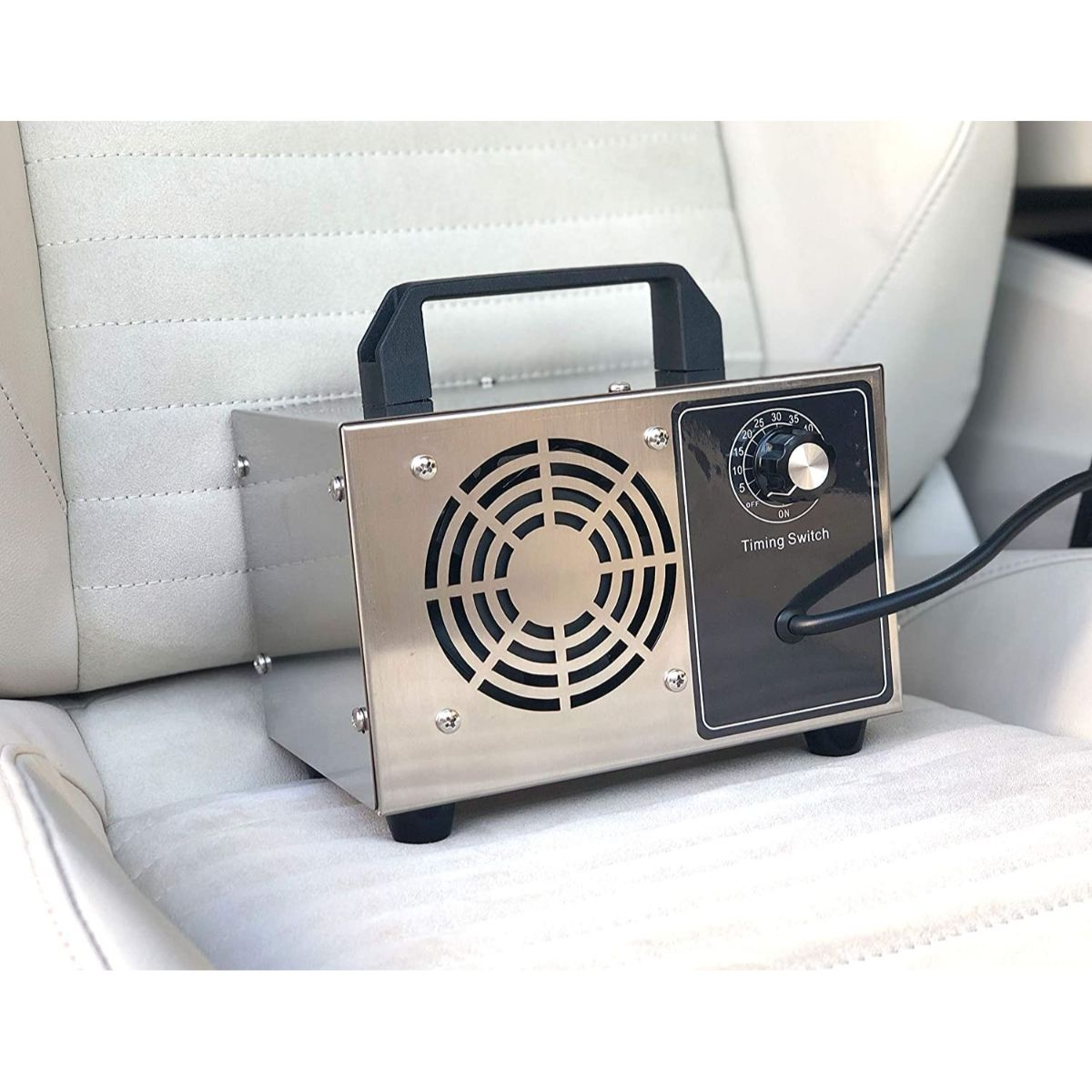 Un purificador de aire plateado en un asiento de coche. Panel de control, ventilador y asa visibles.
