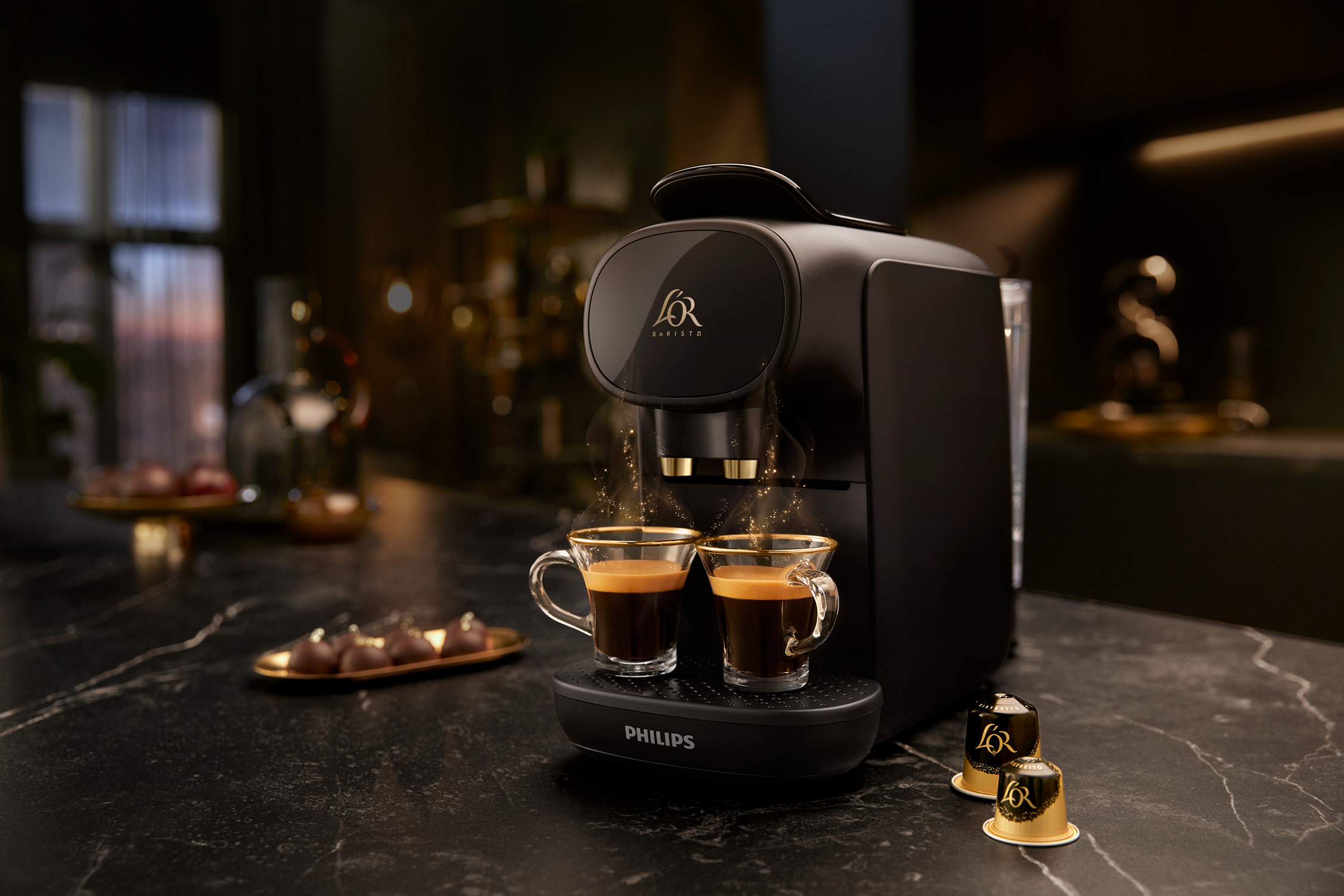 Macchina da caffè nera con due tazze di espresso. Due cialde di caffè a destra.