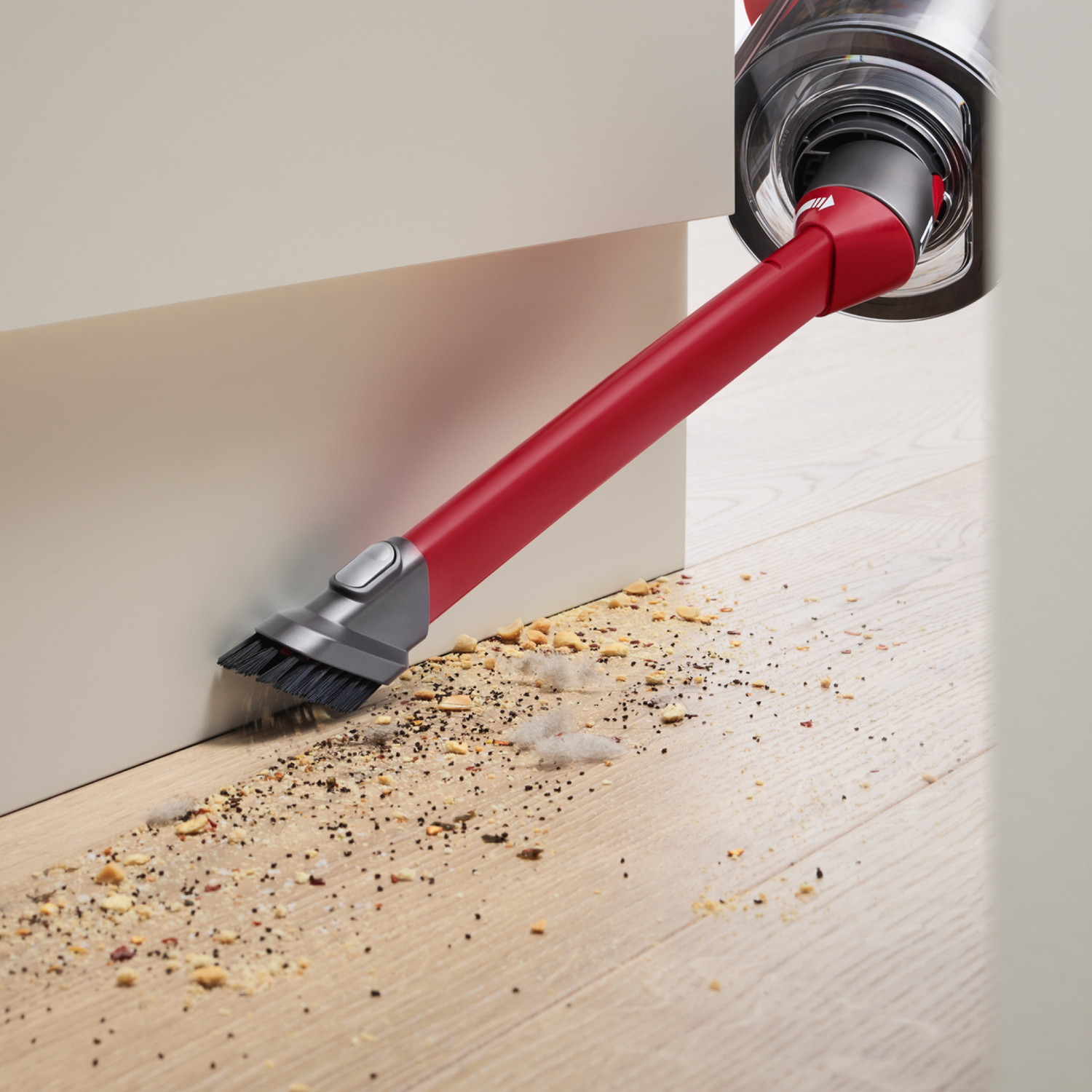 Czerwone mocowanie odkurzacza czyszczące drewnianą podłogę, usuwające okruchy w pobliżu białej szafki.
