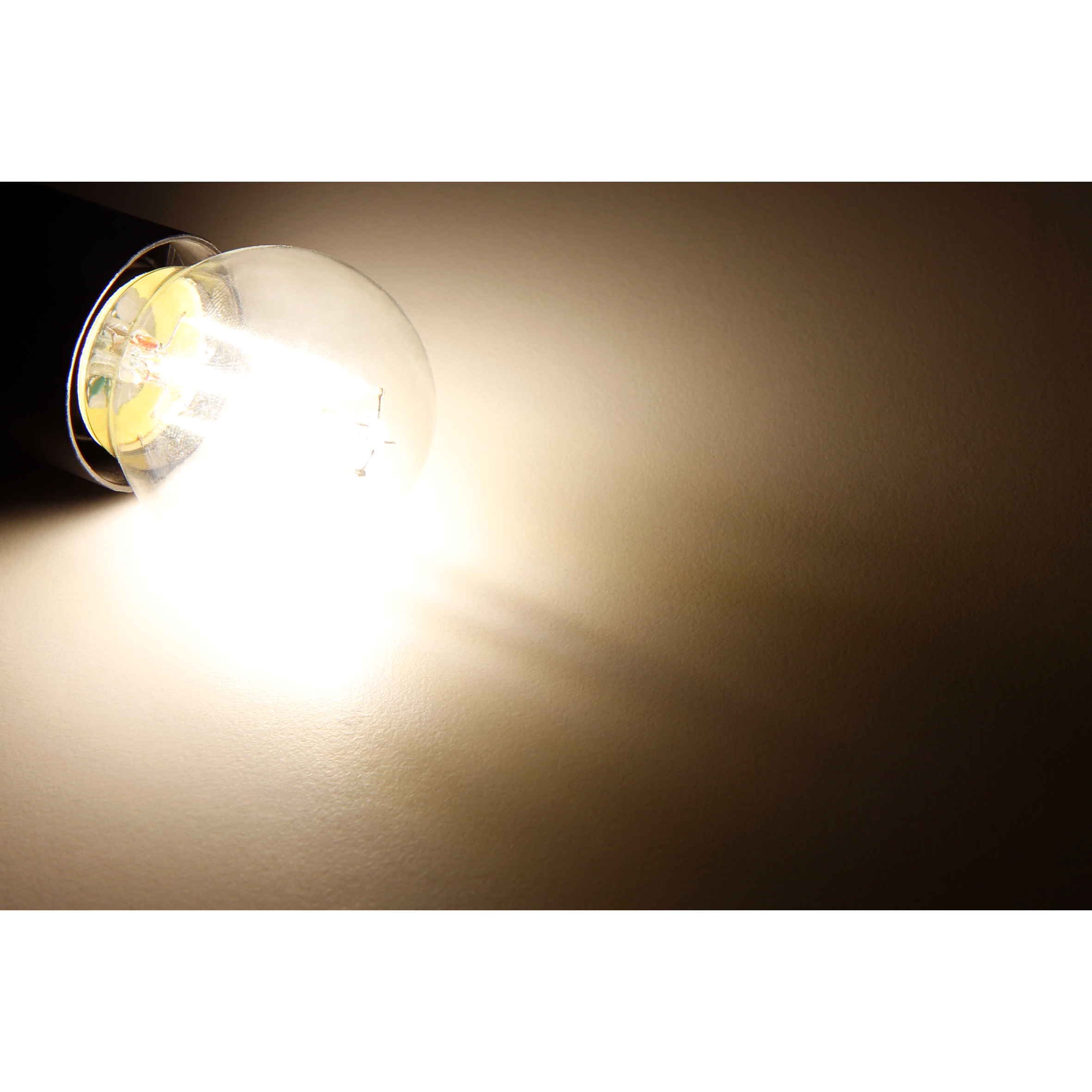 Nahaufnahme einer Glühbirne, die helles Licht an eine Wand abgibt.