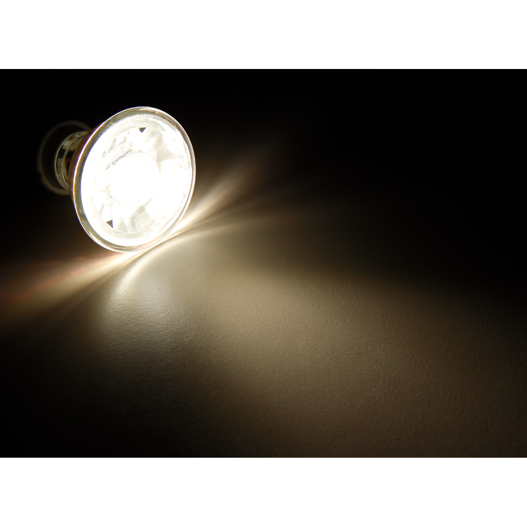 Eine helle Glühbirne, die Licht auf einem dunklen Hintergrund abstrahlt. Das Licht fokussiert rechts.