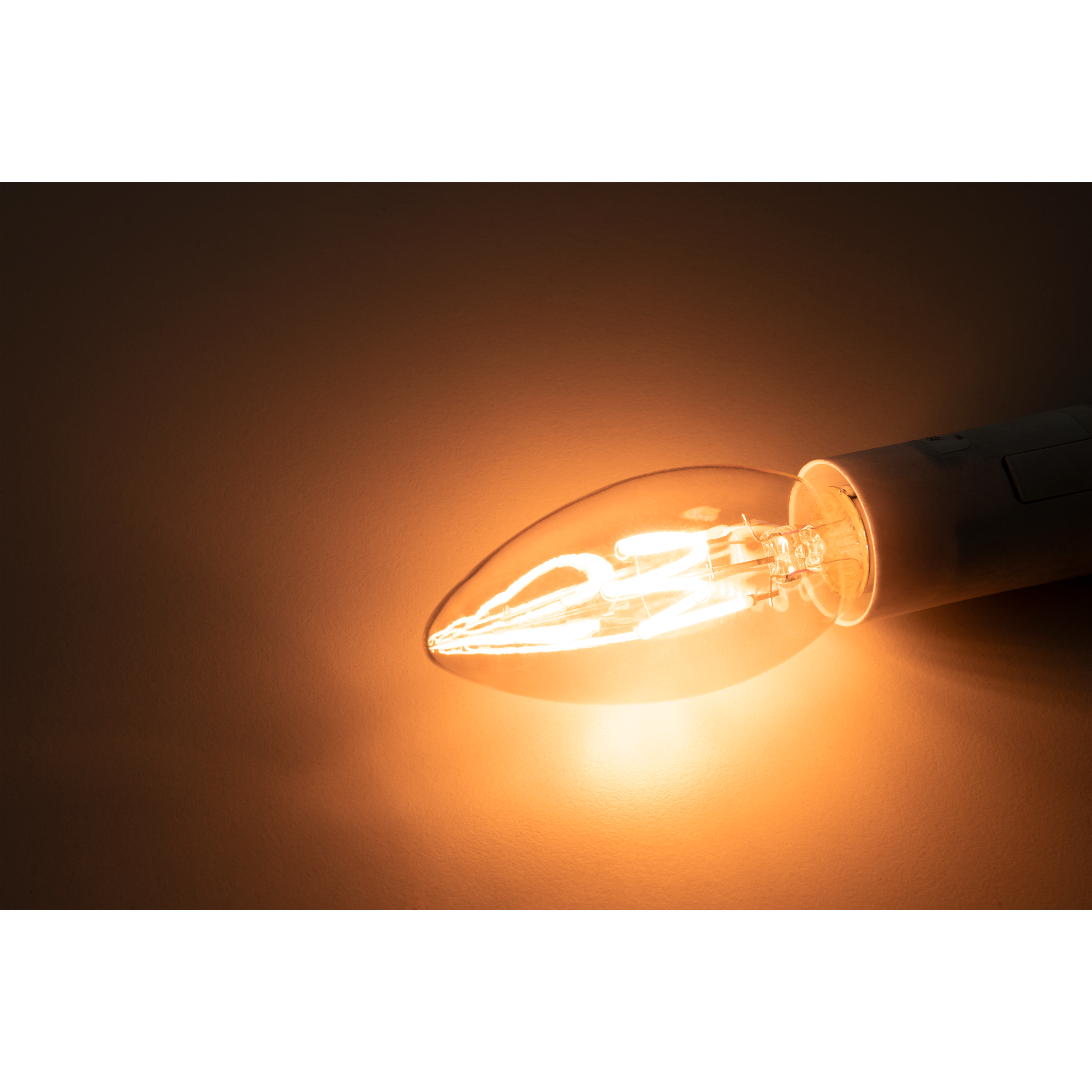 Leuchtmittel leuchtet, zeigt einen glühenden Glühfaden. Der Hintergrund ist ein Farbverlauf von Braun und Schwarz.