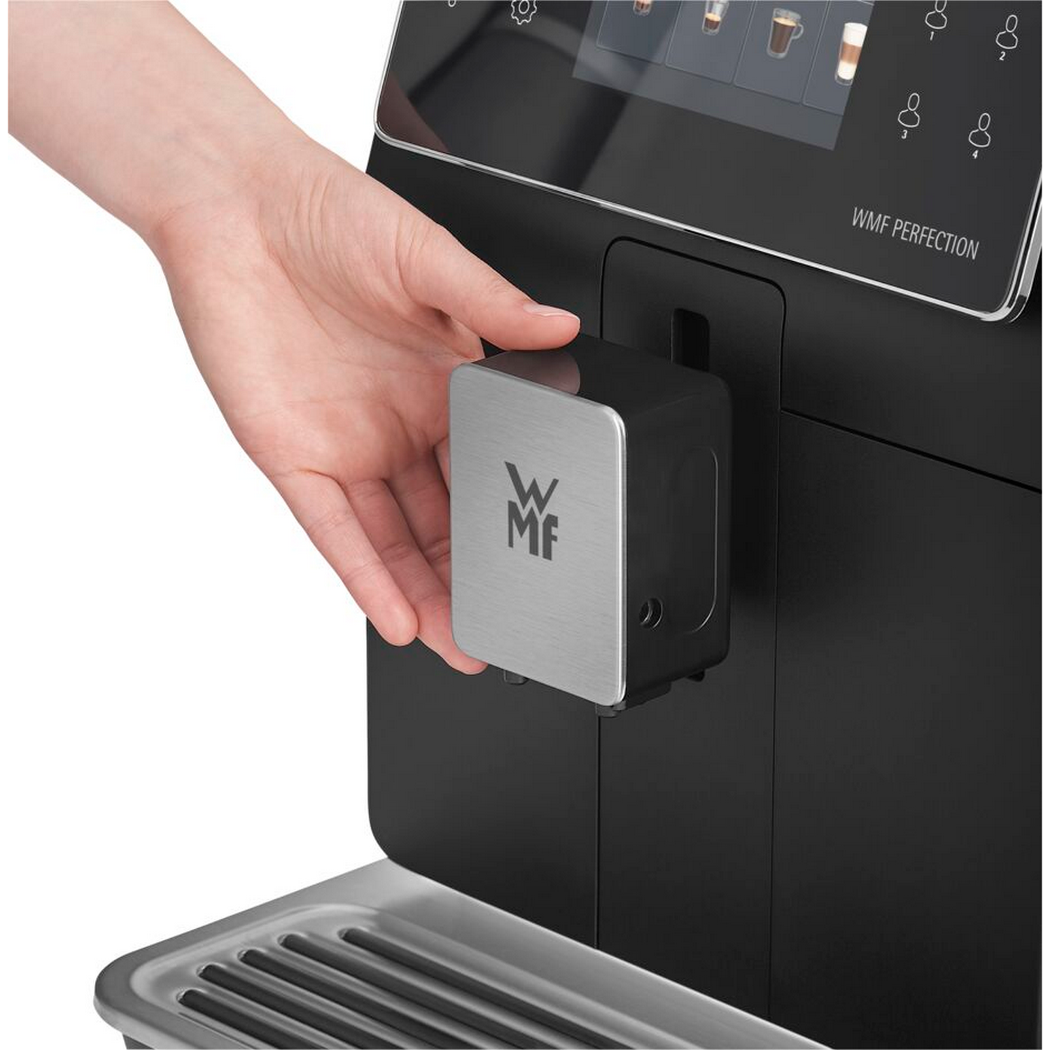 Ręka otwiera pojemnik ekspresu do kawy, z logo WMF, czarna maszyna, srebrna taca.