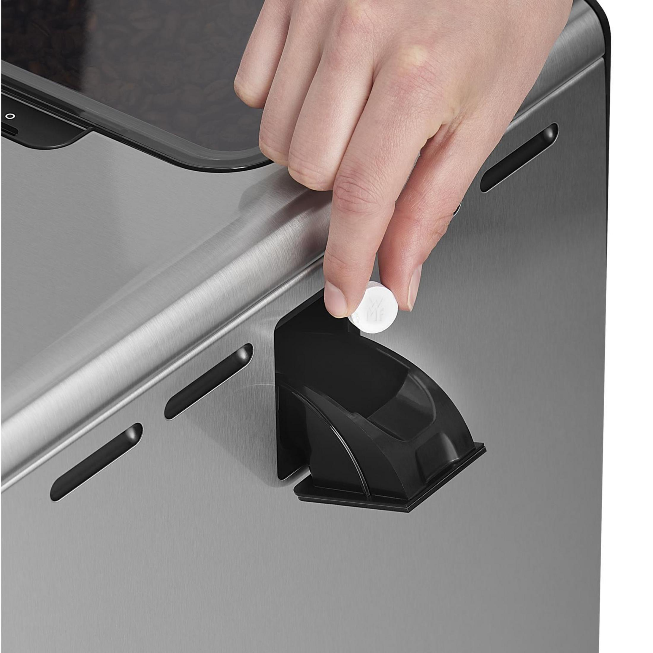 Ręka wkładająca biały dysk do czarnego elementu ekspresu do kawy.