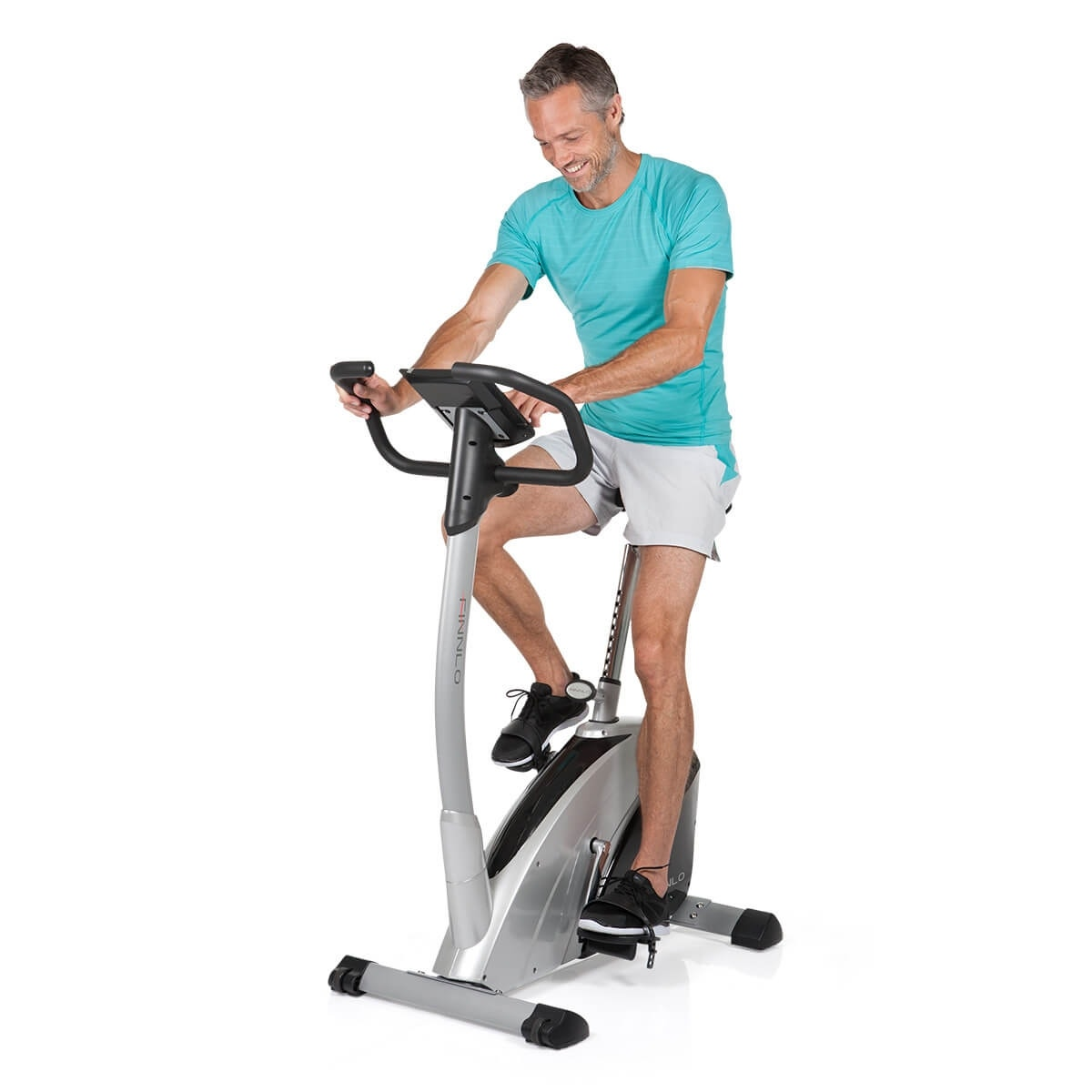 Mann auf einem Trainingsfahrrad, lächelnd. Fahrrad ist silber. Weißer Hintergrund.