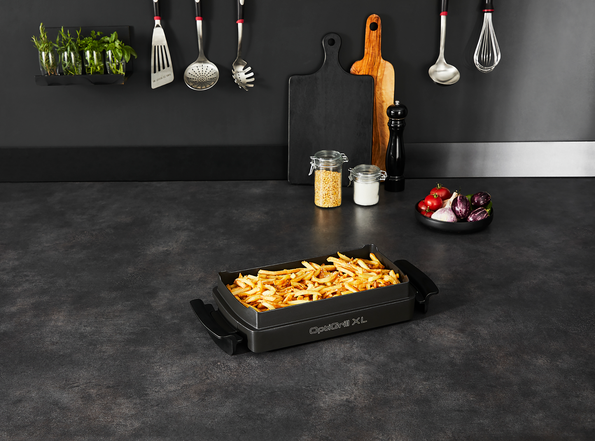 A black grill with french fries, surrounded by kitchen utensils and ingredients on a countertop.