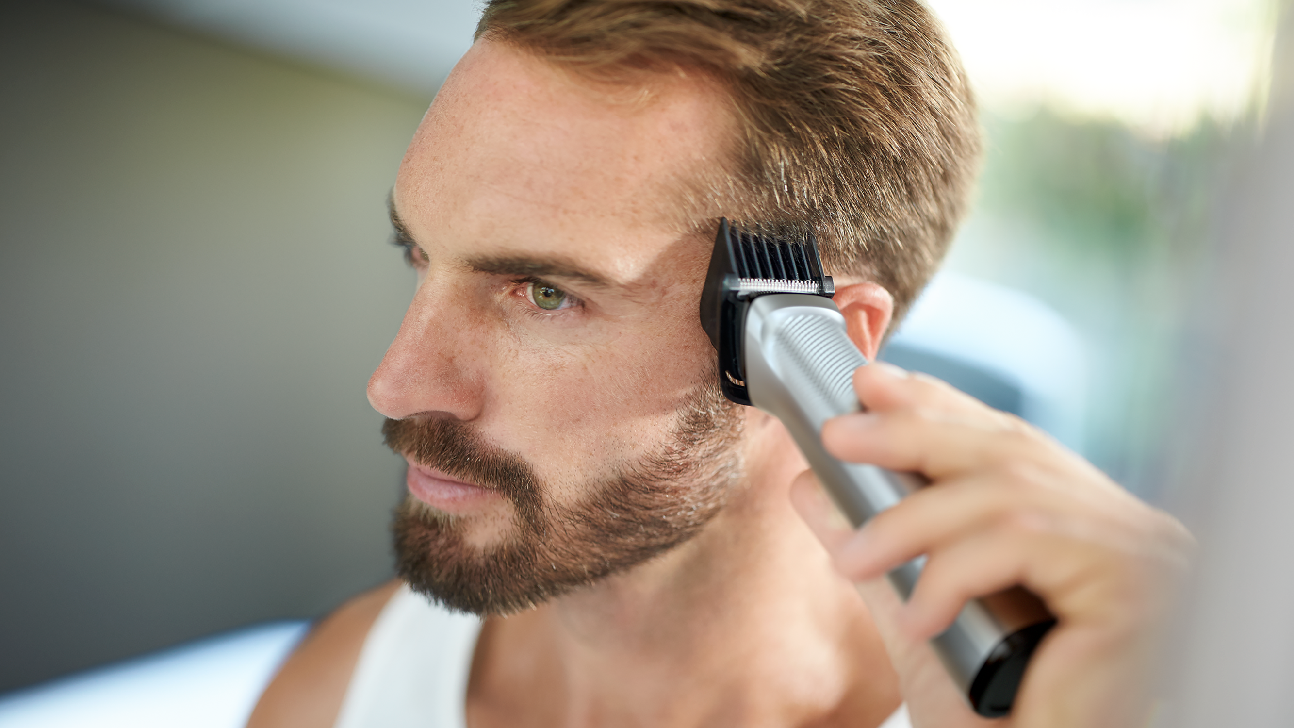 Un uomo sta tagliando la barba con un trimmer elettrico. È nel mezzo del processo.