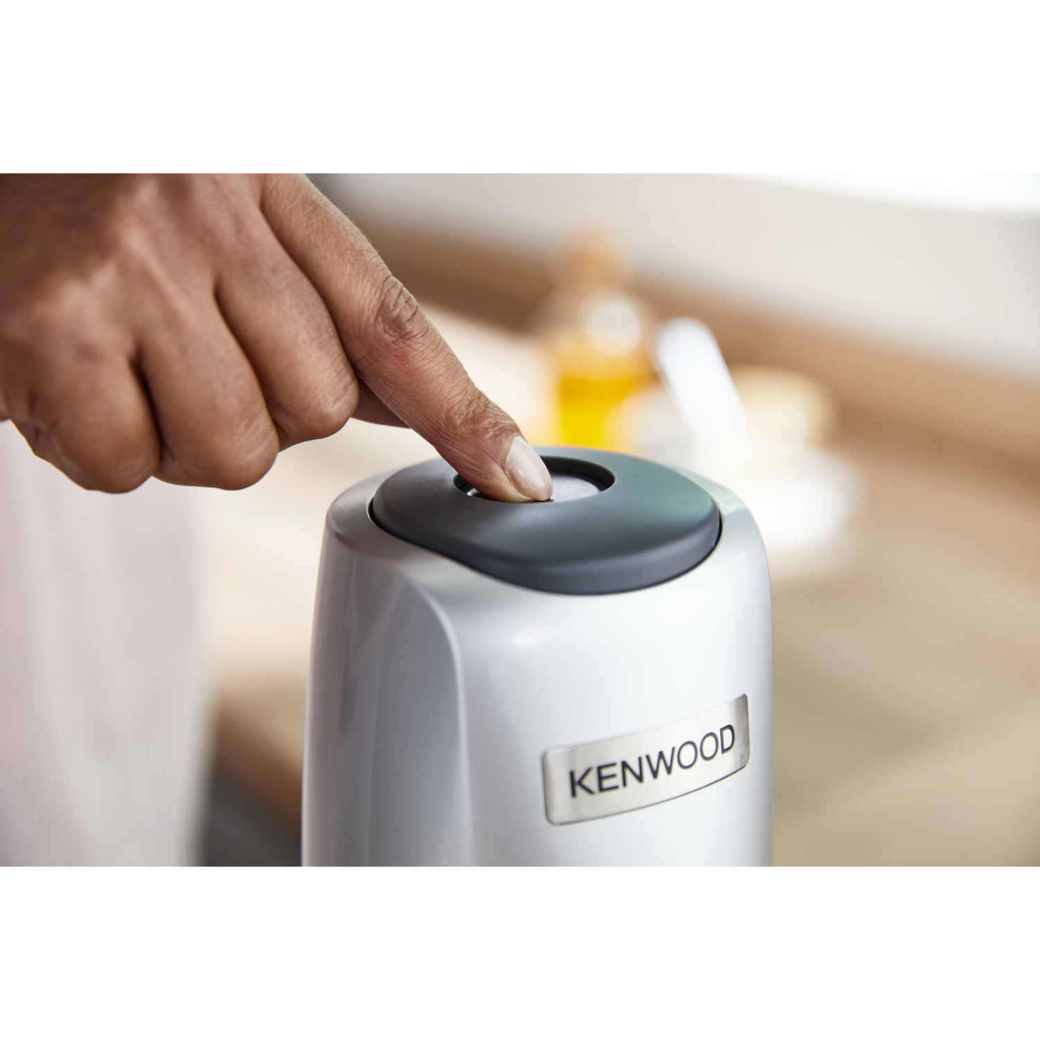Bir kişinin parmağı, gümüş rengi bir Kenwood cihazındaki bir düğmeye basıyor.
