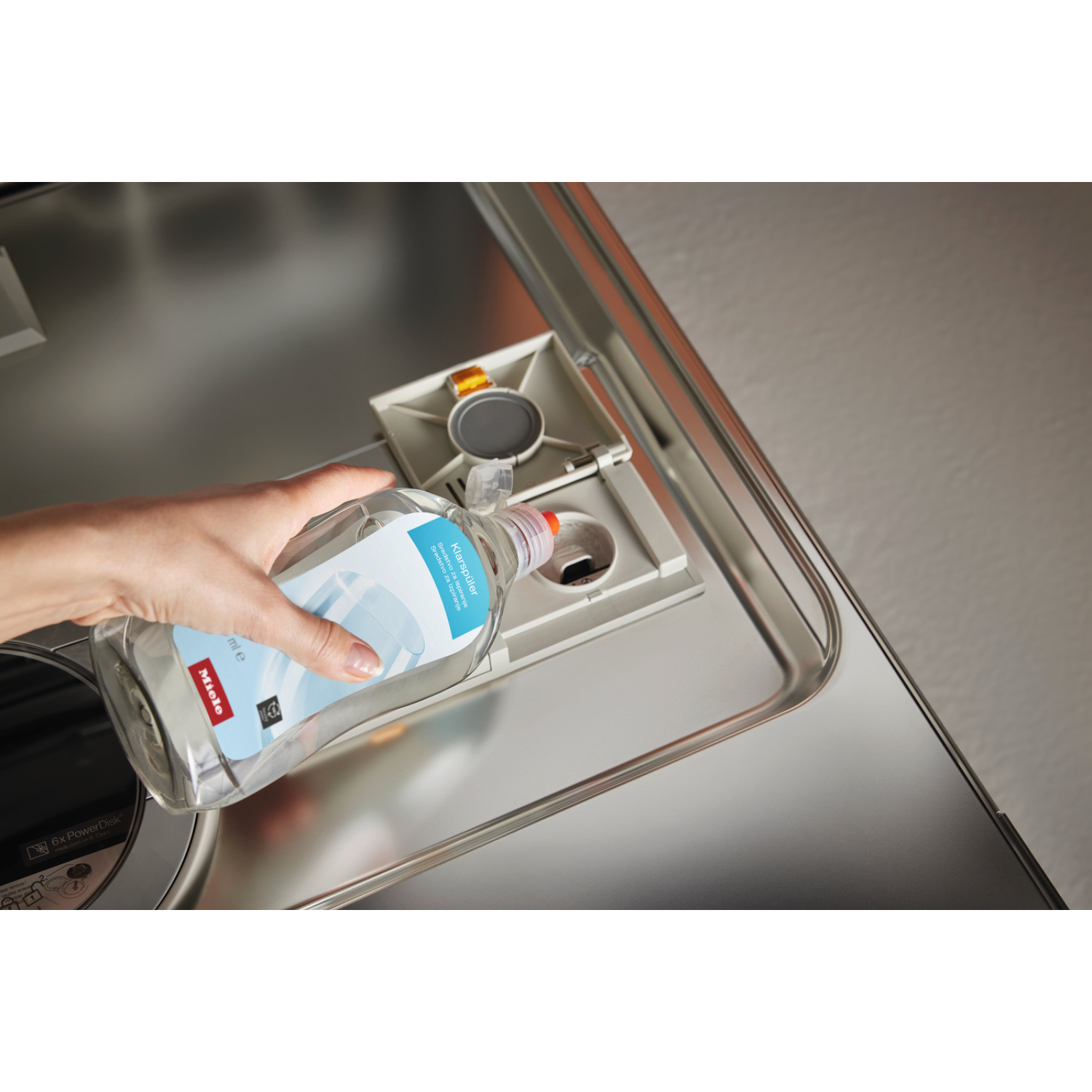Mano che versa detersivo liquido in un dispenser per lavastoviglie.