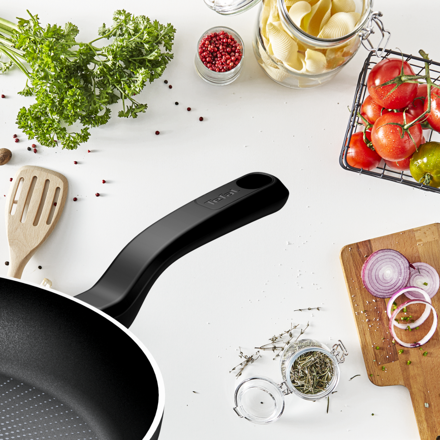 Pans, ingredients, and vegetables on white surface.