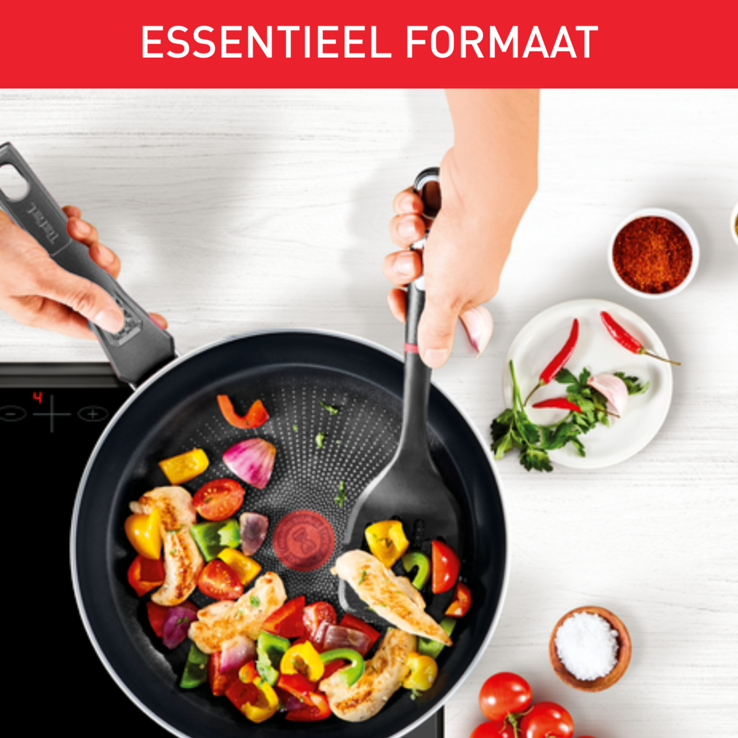 Pan with vegetables and chicken being stirred. White table. Words 'ESSENTIEEL FORMAAT' on top.