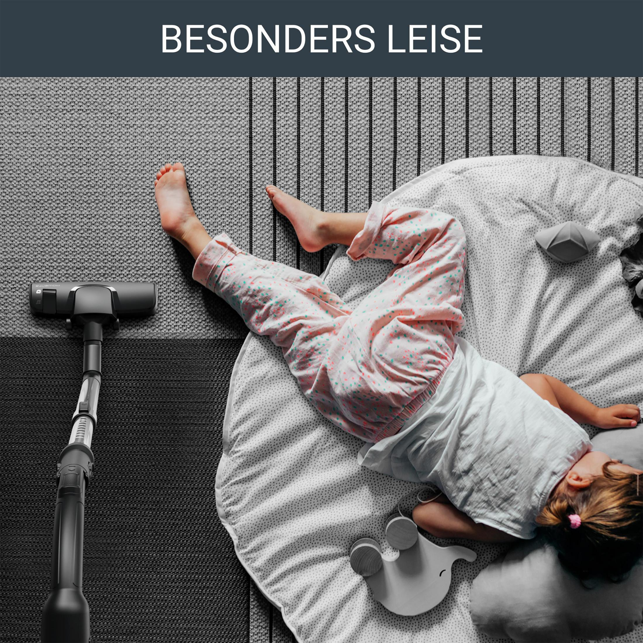 Dziecko śpi na dywanie podczas odkurzania. Odkurzacz i tekst 'BESONDERS LEISE' widoczne.