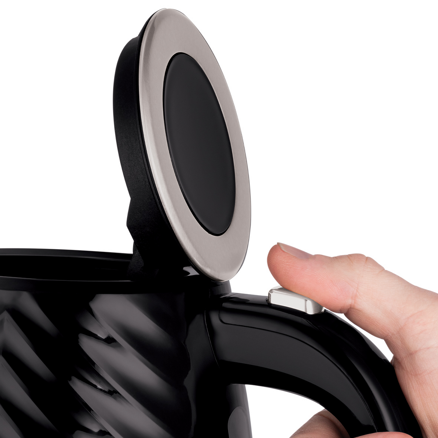 Ręka naciska biały przycisk na czarnym czajniku. Pokrywa jest otwarta.