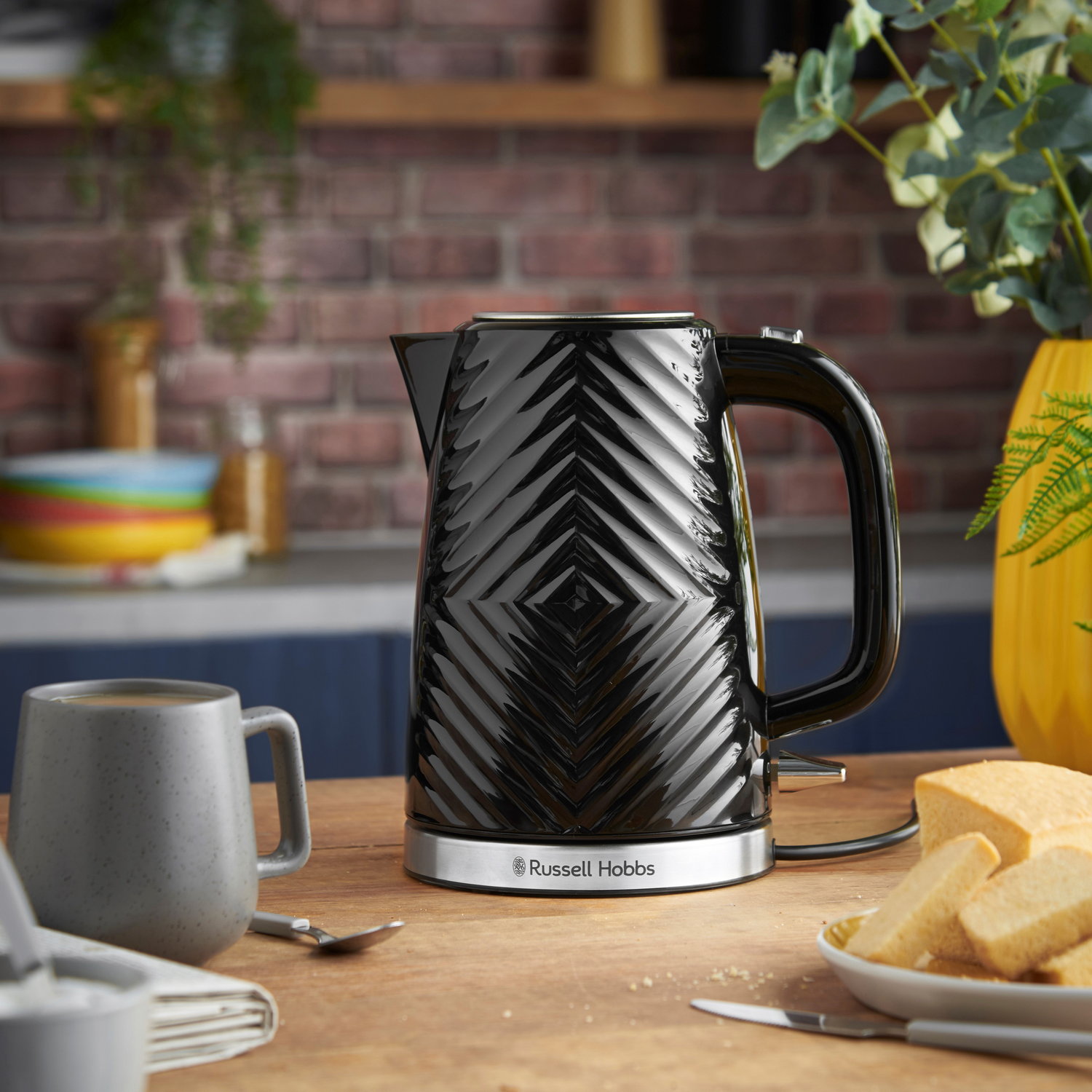 Czarny czajnik elektryczny w wzory z czarnym uchwytem. Stoi na drewnianej powierzchni.