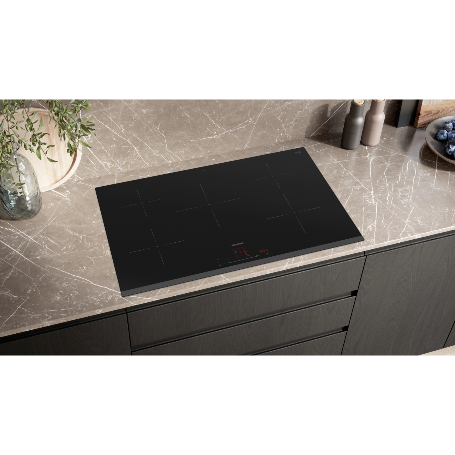 Table de cuisson à induction noire sur un comptoir en marbre. Portes de placard en arrière-plan.