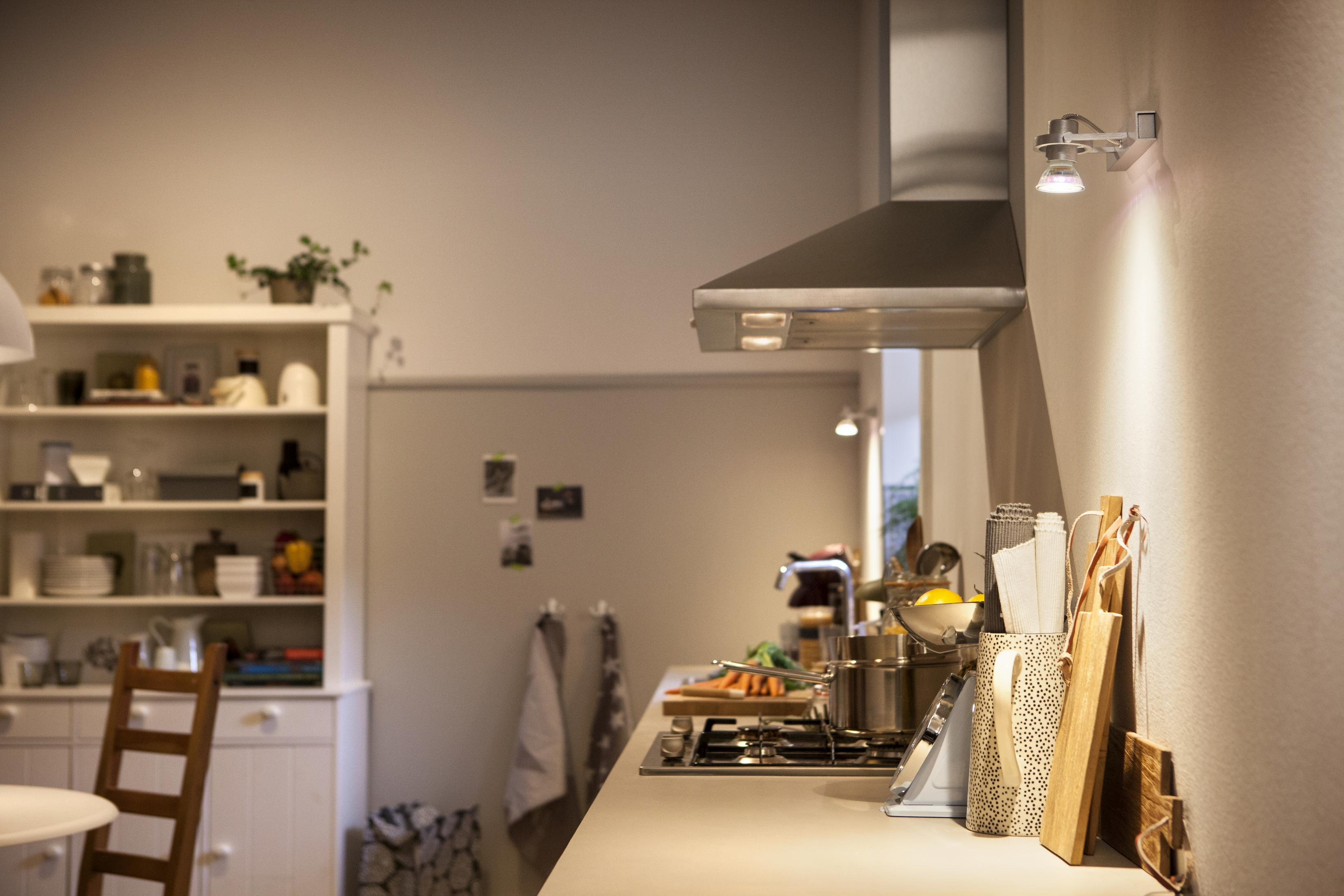 Een keukeninterieur met een fornuis, een wandlamp en een witte kast. De scène is goed verlicht.