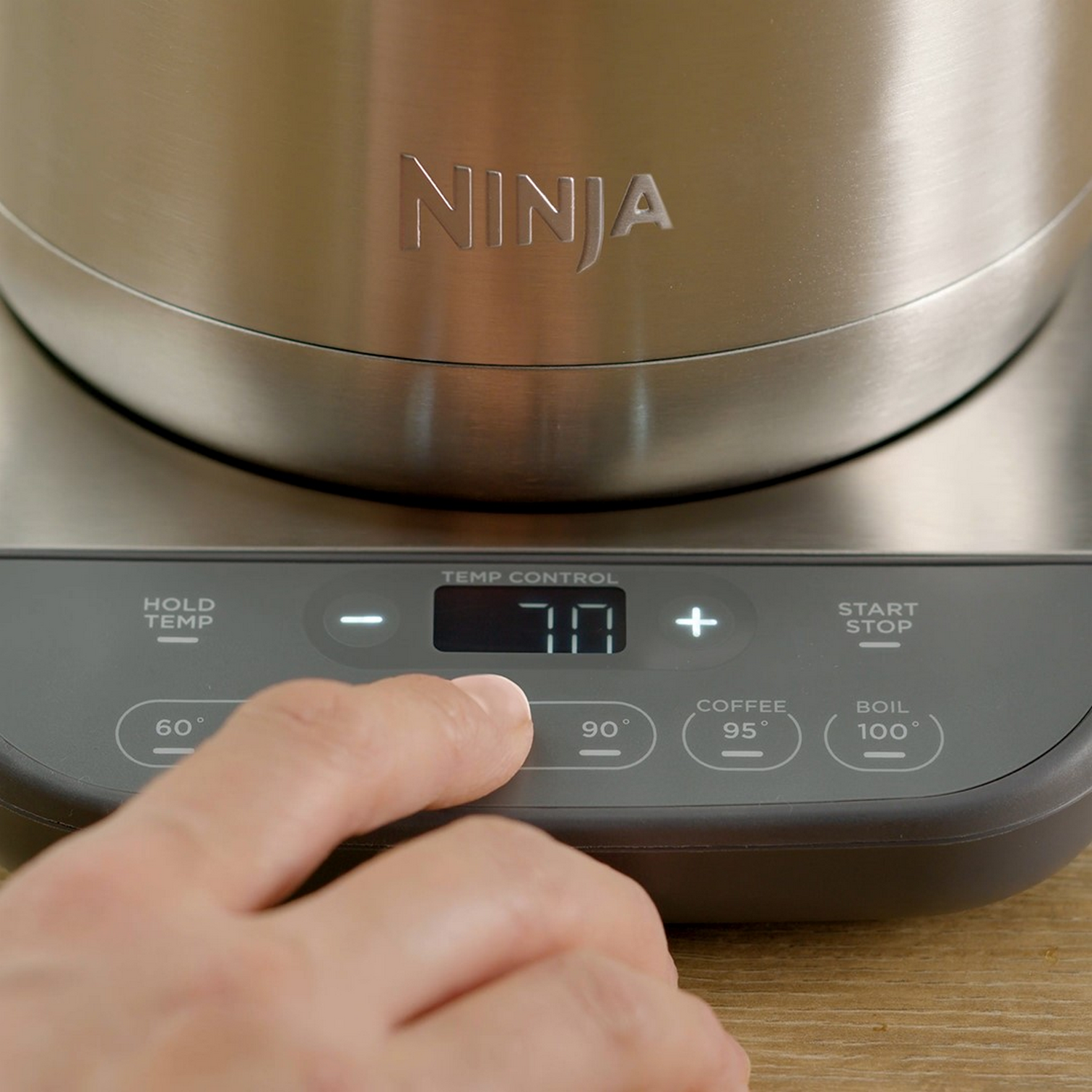 Zbliżenie panelu sterowania ekspresu do kawy, z palcem naciskającym przycisk.