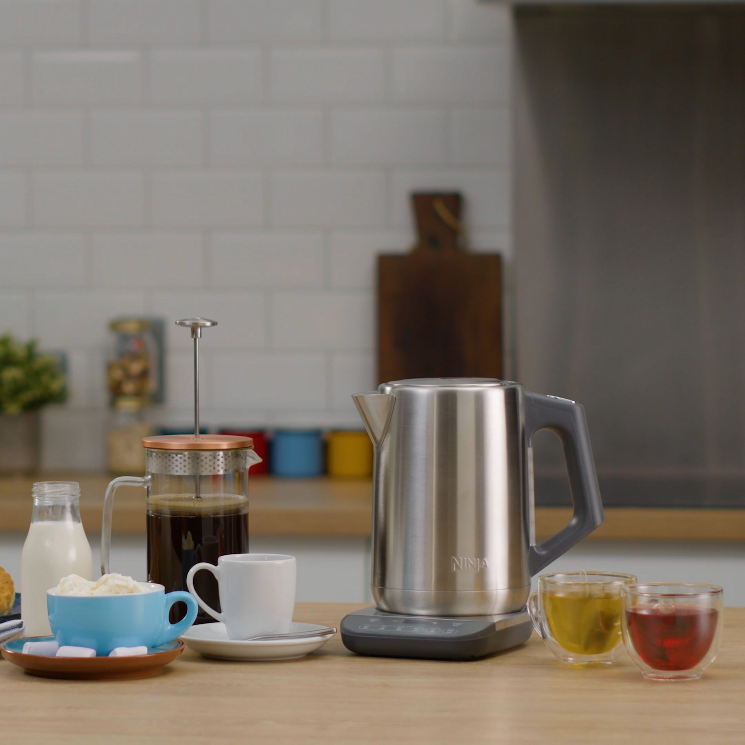 Scena kuchenna z czajnikiem i akcesoriami do parzenia kawy. Niebieski kubek i przezroczyste szklanki.