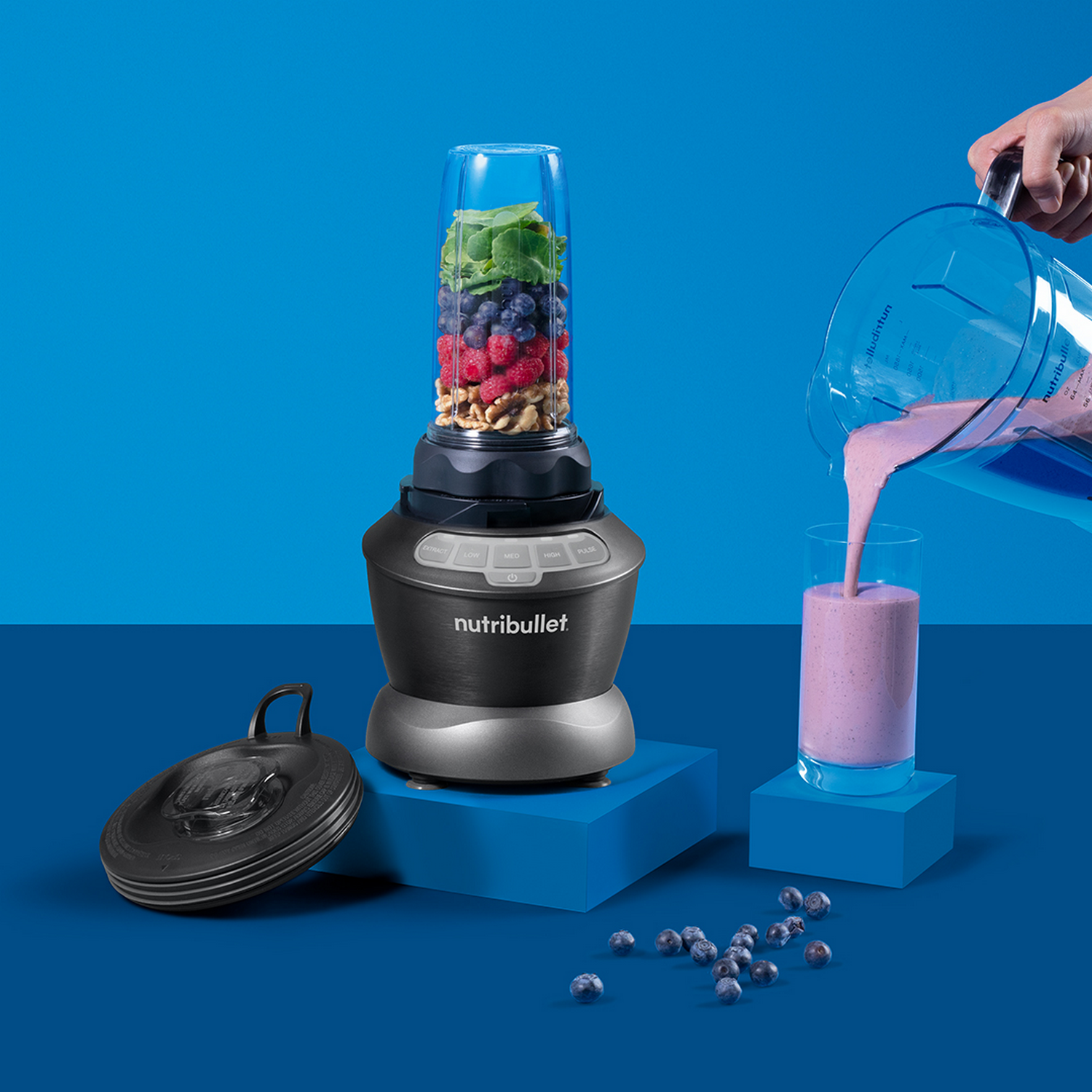 Un mixeur avec des ingrédients à l'intérieur et une main versant le smoothie dans un verre.