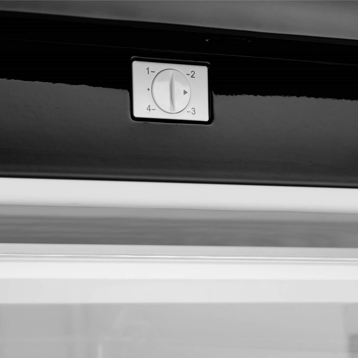 Close up of a refrigerator temperature control panel with a dial numbered 1-4, and a black surface.