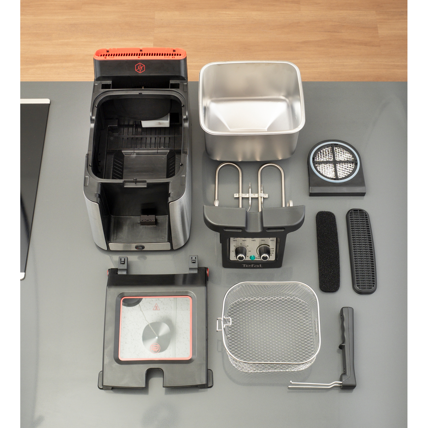 Rozmontowana frytkownica. Kilka części rozłożonych na szarej powierzchni.