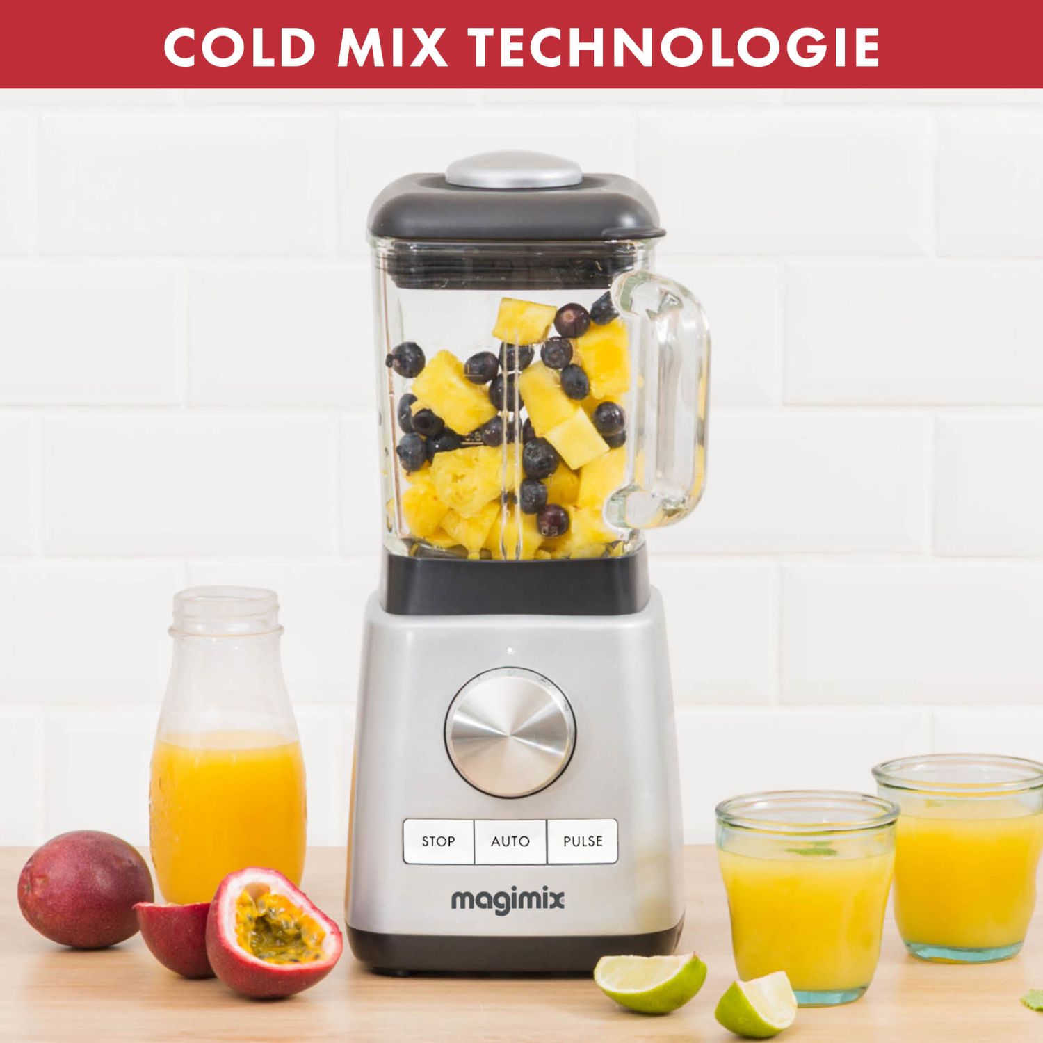 A silver blender with fruit inside. Next to it, there are glasses of juice and fresh fruit.