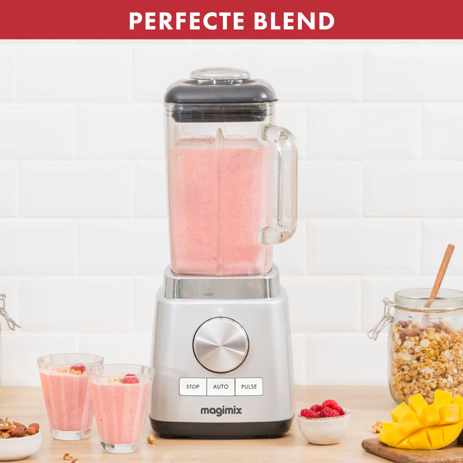 Blender met roze smoothie, twee glazen met smoothie en fruit op een houten tafel.
