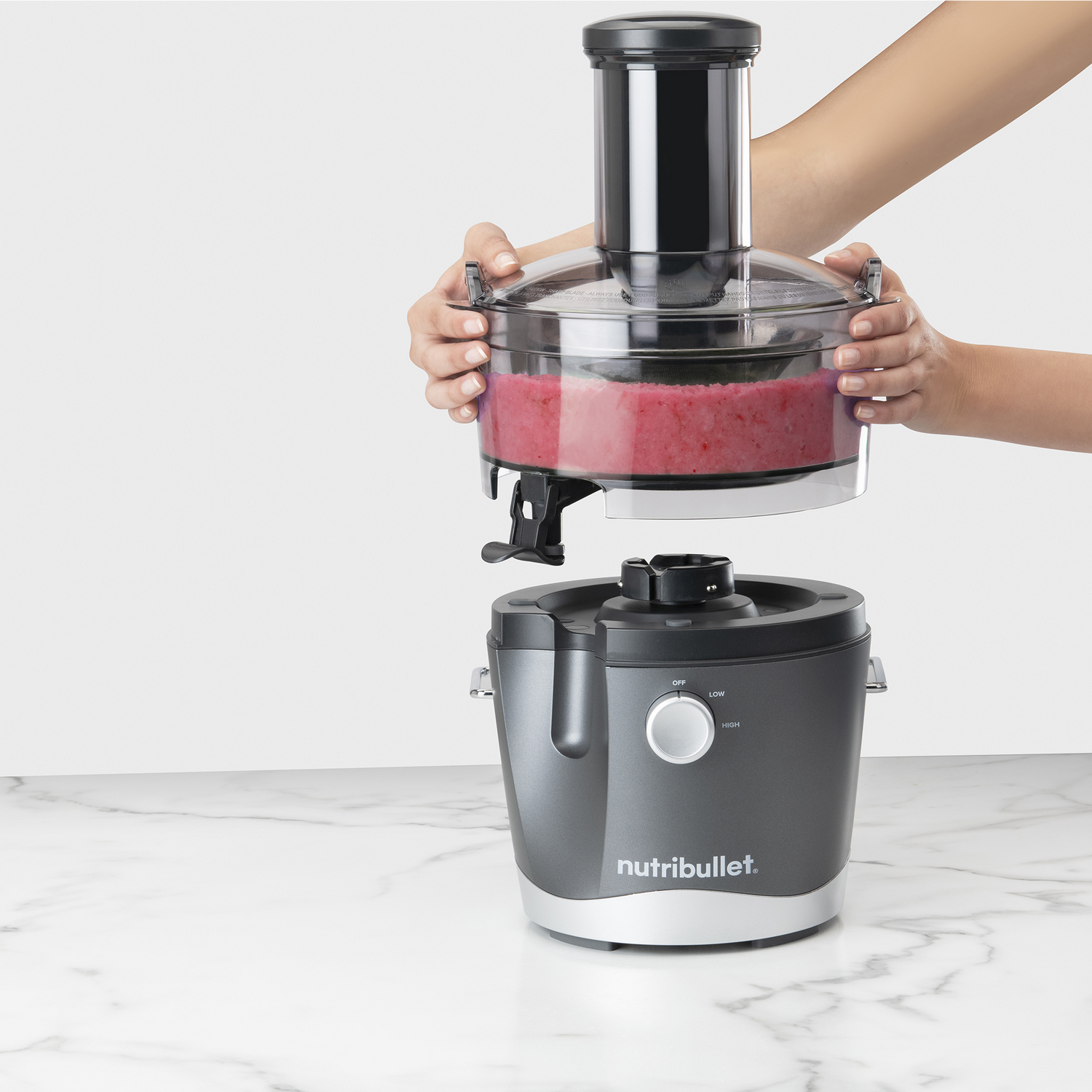 A Nutribullet blender with a container of red blended food being assembled.