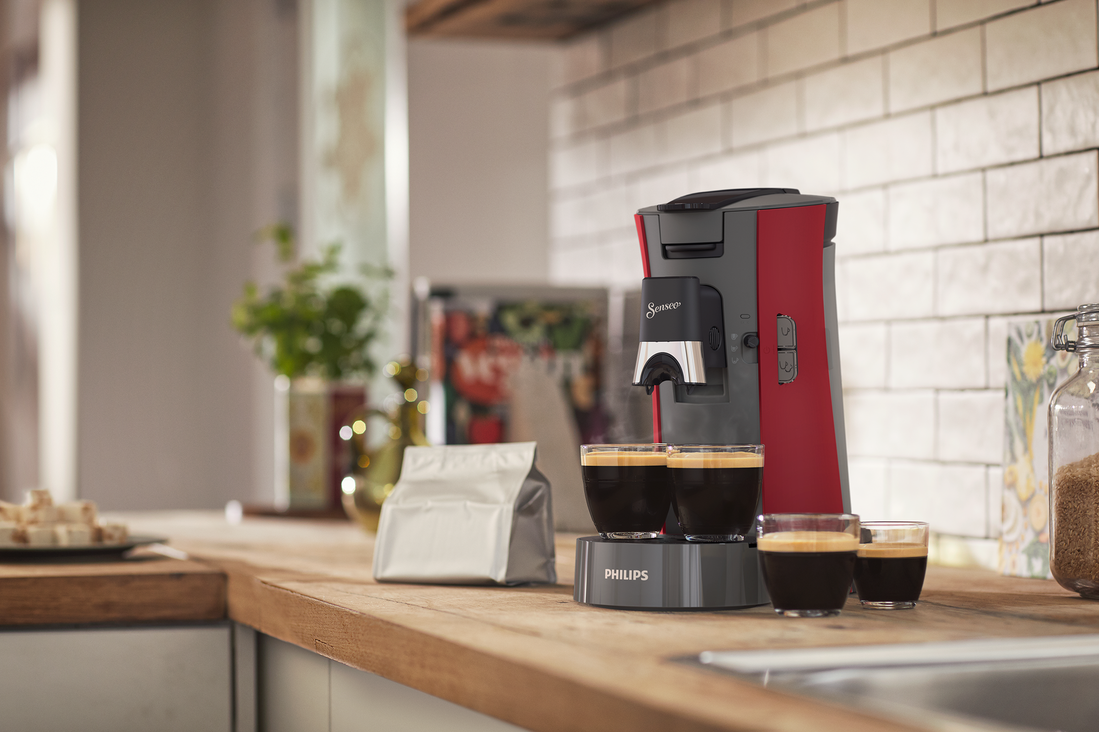 Czerwono-szara ekspres do kawy Philips Senseo z filiżankami i akcesoriami.