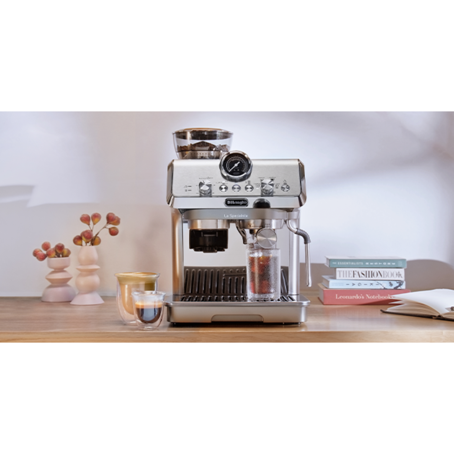 Ekspres do kawy na drewnianym stole. Obok filiżanki i książki. Neutralne tło.