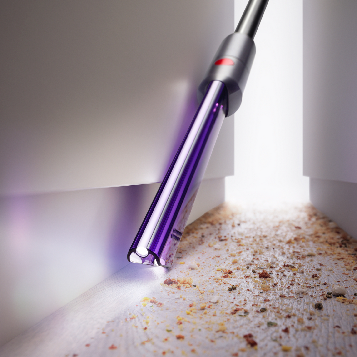 Un aspirapolvere viola con una luce che pulisce un angolo del pavimento.