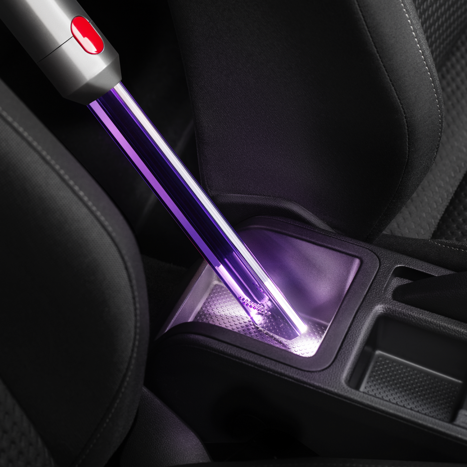 Un aspirapolvere portatile pulisce la console centrale dell'auto.