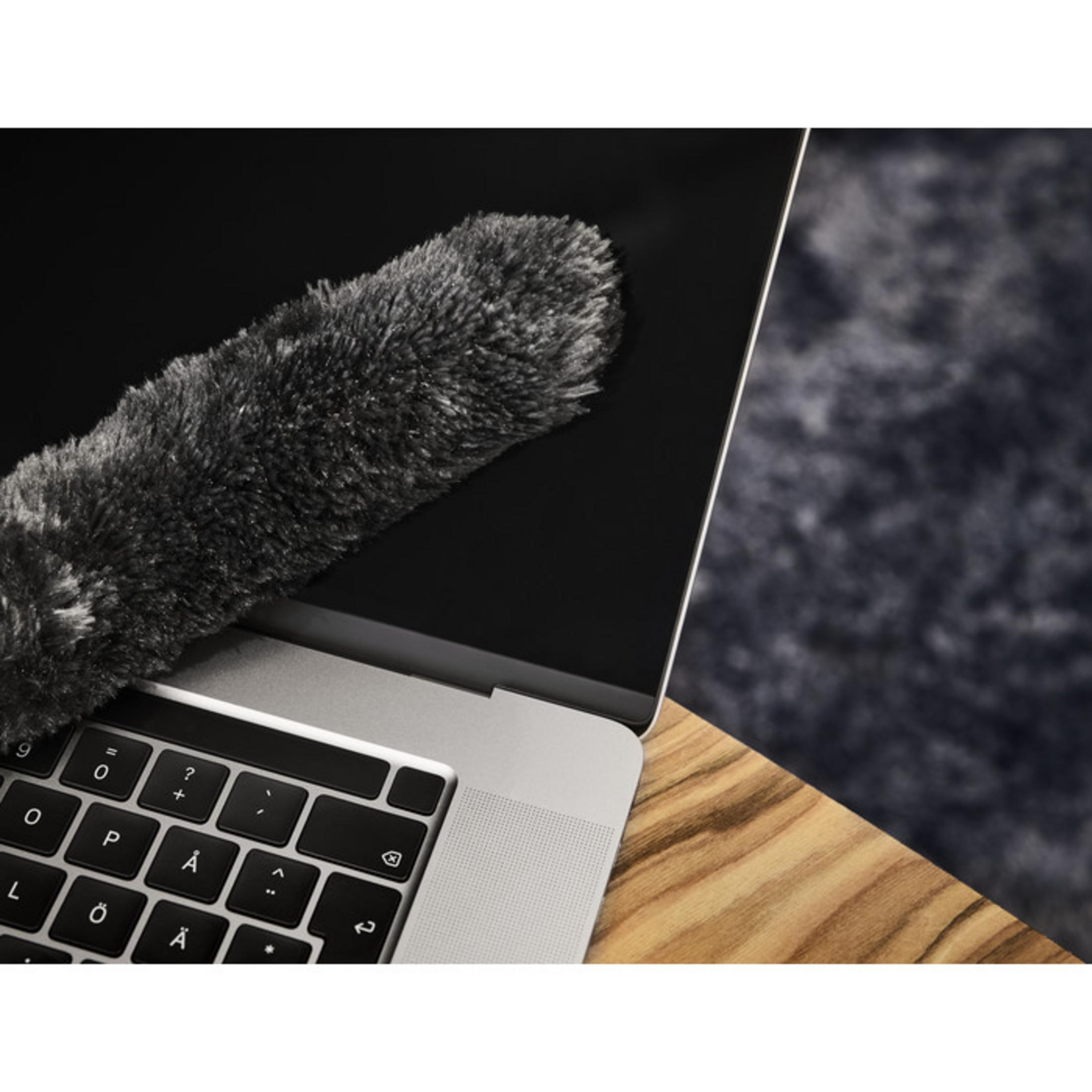 Laptop z ekranem czyszczonym przez szarą miotełkę na drewnianym stole.