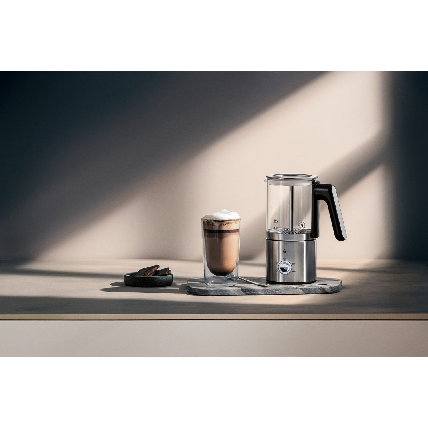 Spieniacz do mleka ze stali nierdzewnej ze szklanką kawy i czekoladą.