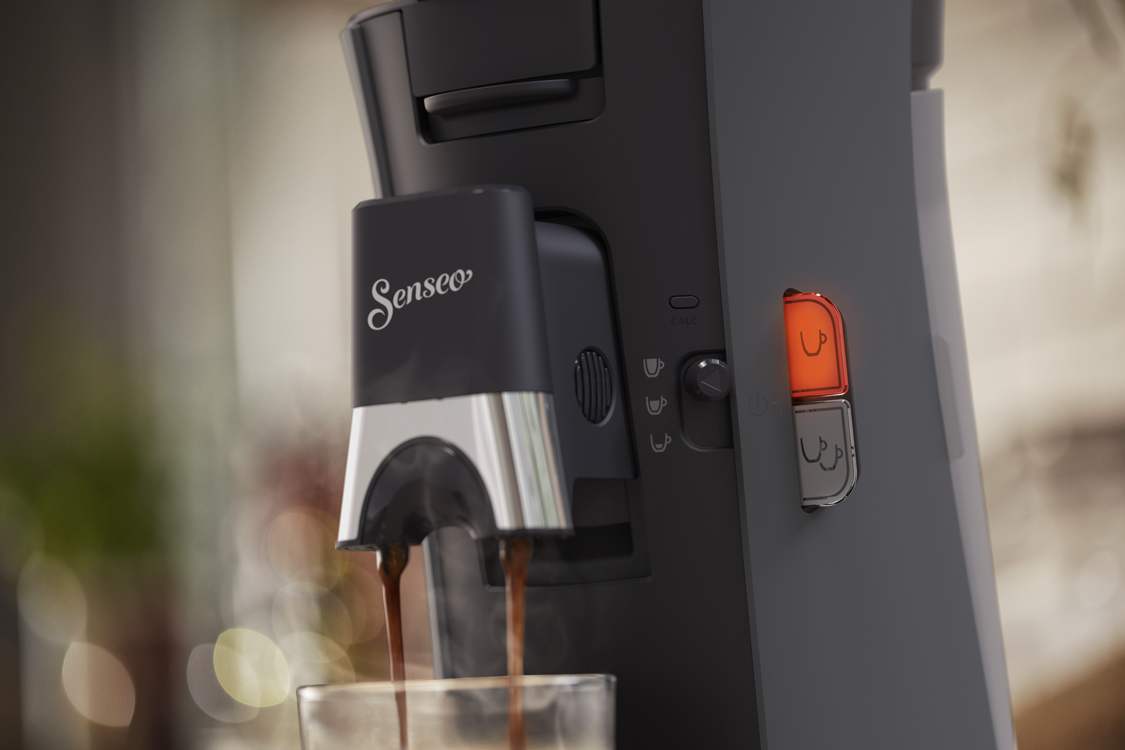 Czarny ekspres do kawy Senseo, z dwiema filiżankami napełnianymi kawą i czerwonymi przyciskami.