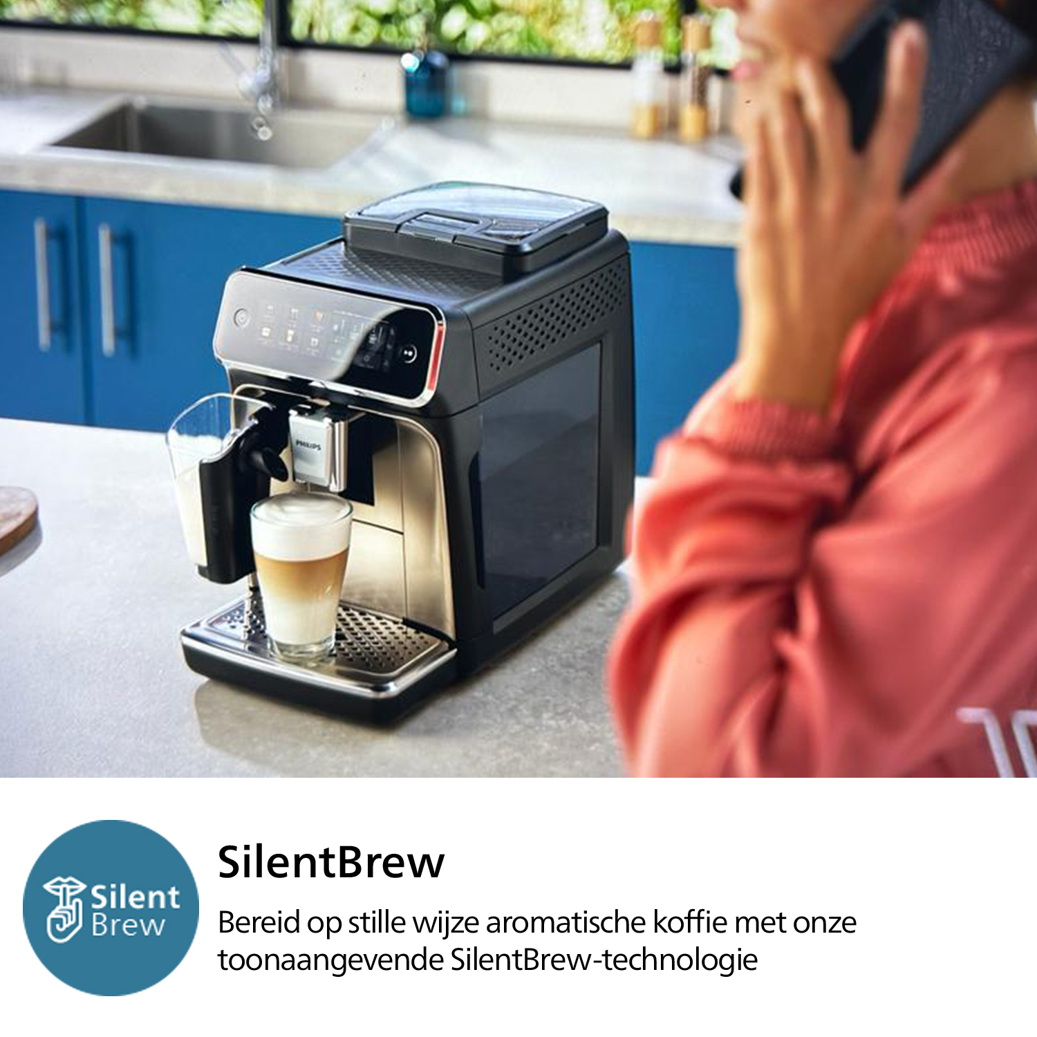 Cafetera preparando un latte. Mujer hablando por teléfono en el fondo. Cocina azul.