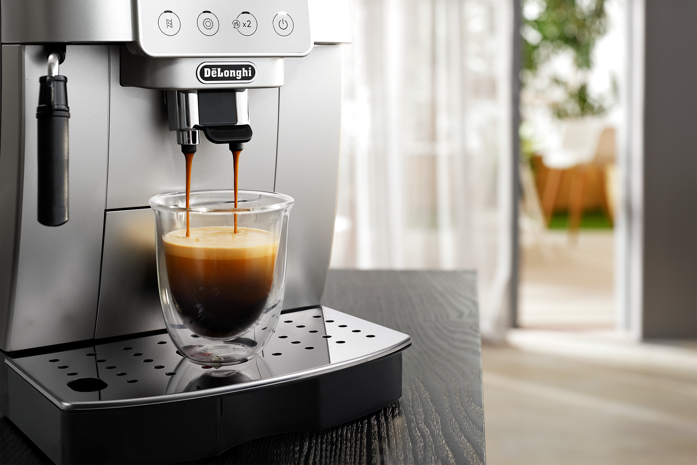 Espresso machine pouring coffee into a glass cup. Black table, blurred background.