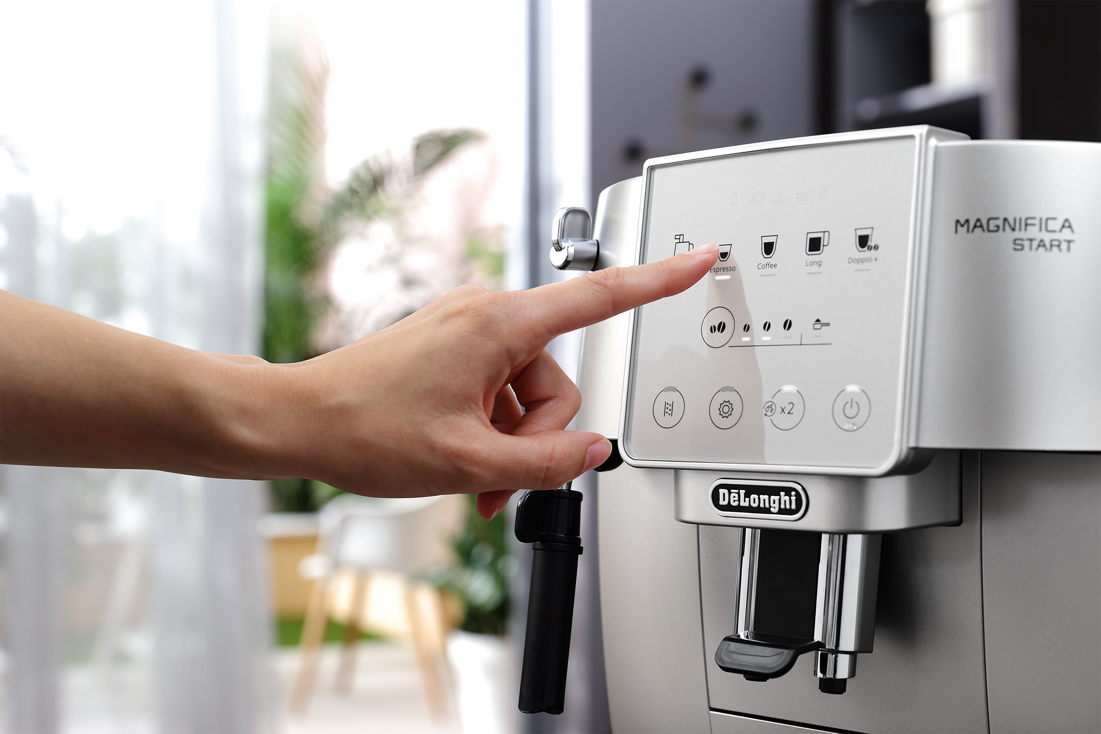 Hand pressing a button on a coffee machine. The brand Delonghi is visible.