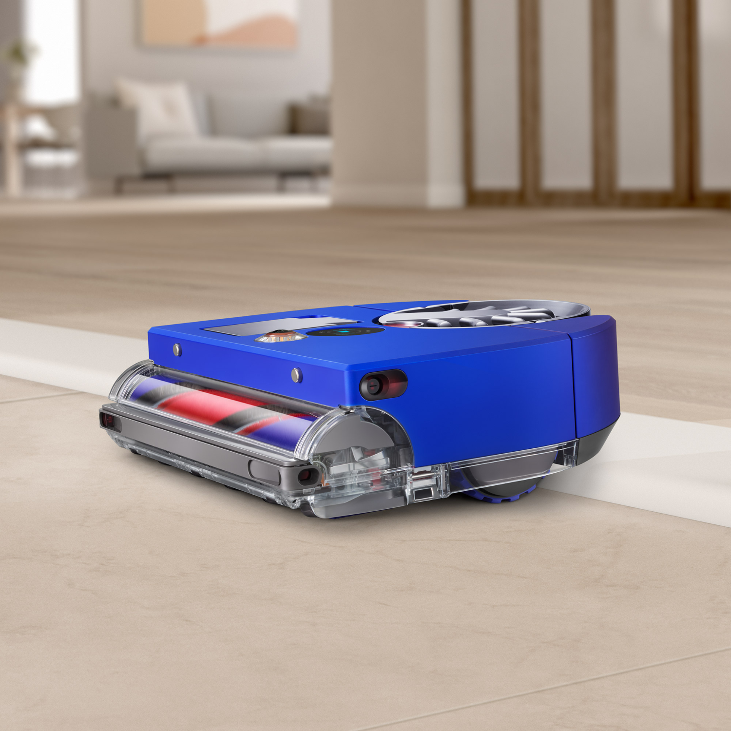 Ein Roboter-Staubsauger in Blau und Transparent mit roten und schwarzen Bürsten, auf hellem Boden.