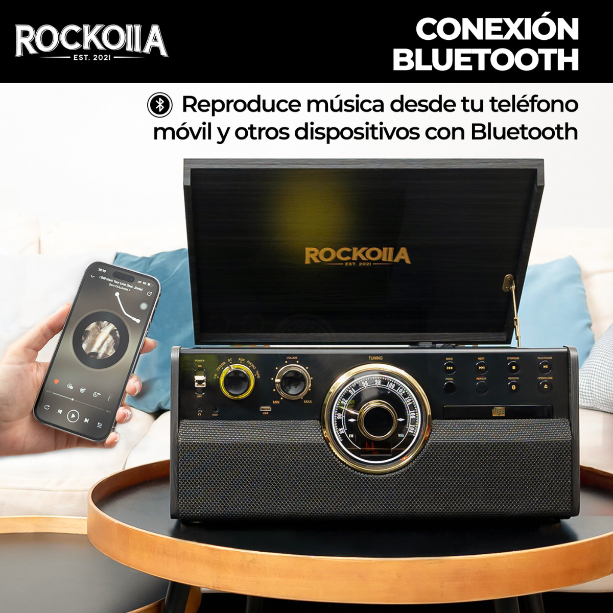 Una radio retro negra reproduce música desde un teléfono. El teléfono muestra una app de música.