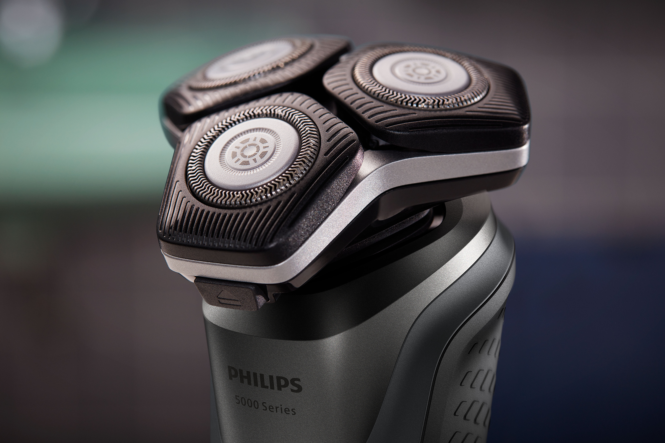 Philips electric shaver, close-up. Three rotary heads visible. Black and silver.