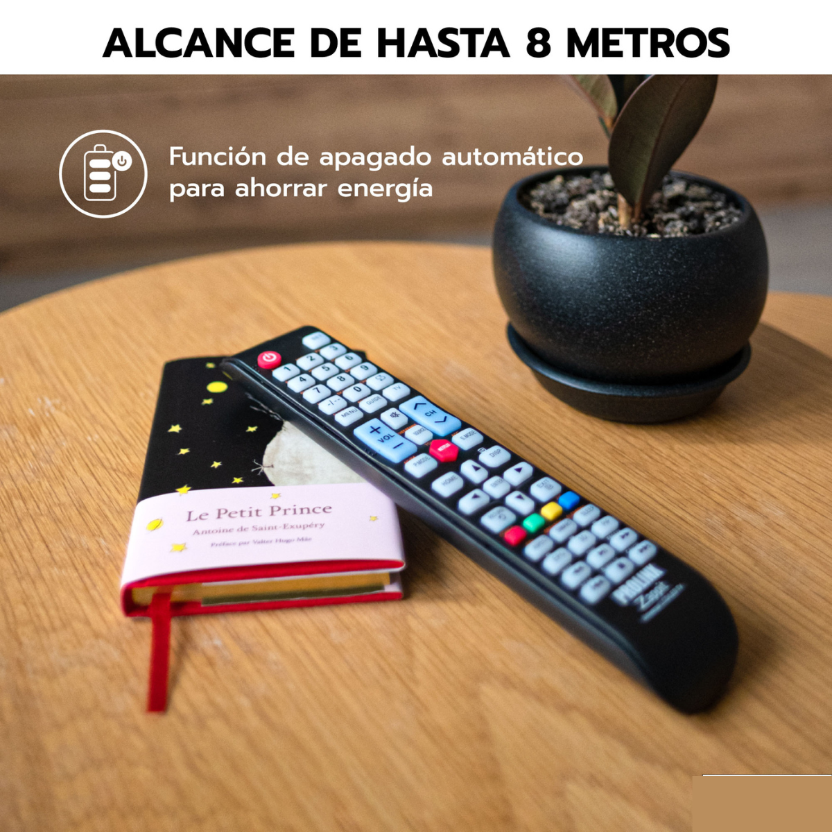 Mando a distancia sobre mesa de madera, libro y maceta pequeña al lado.