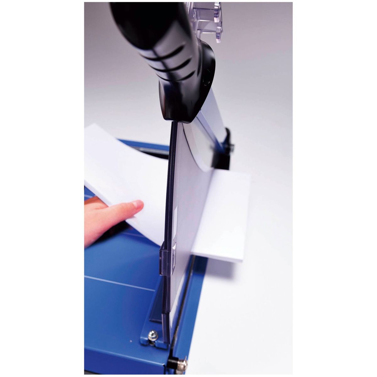 Papierschneider, mit Hand, die ein weißes Blatt führt. Die Klinge ist sichtbar.