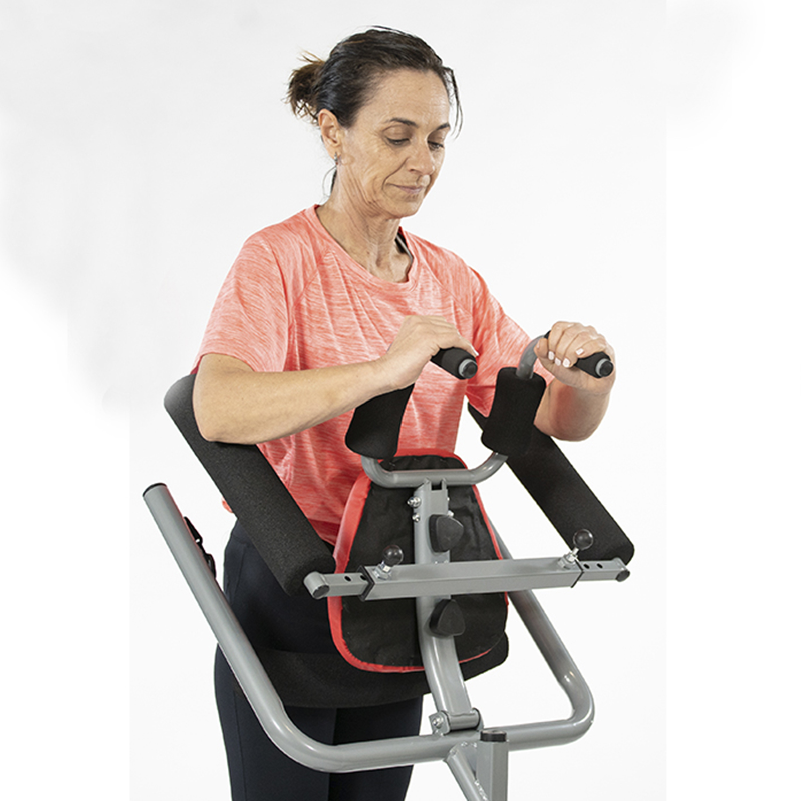 Mujer usando equipo de ejercicio. Mangos, reposabrazos y un asiento. Fondo blanco.