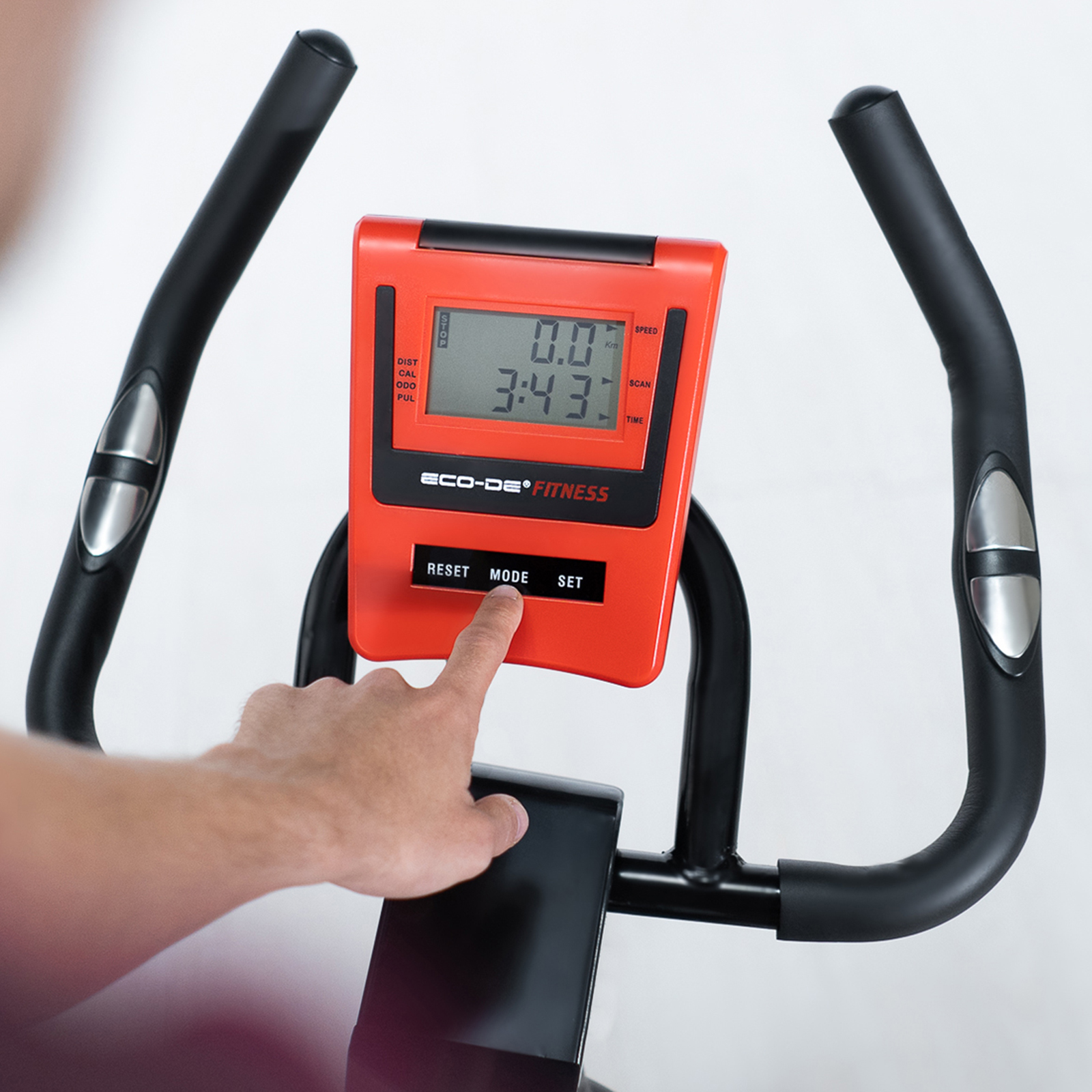 Persona usando una bicicleta estática. Están pulsando un botón en la pantalla. La pantalla muestra datos.