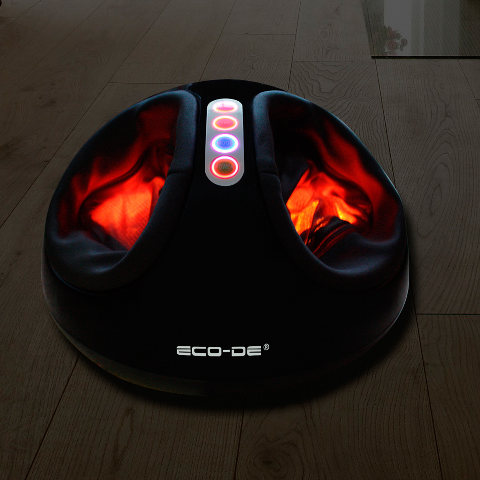 Masajeador de pies negro. Luces y luz roja brillando dentro. Colocado en suelo de madera.